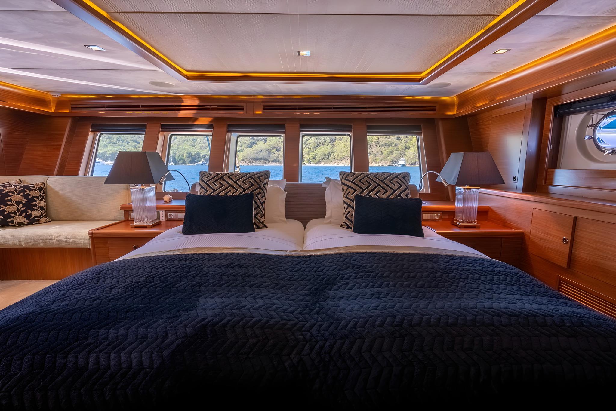 luxury yacht master cabin featuring king bed with navy bedding and panoramic windows