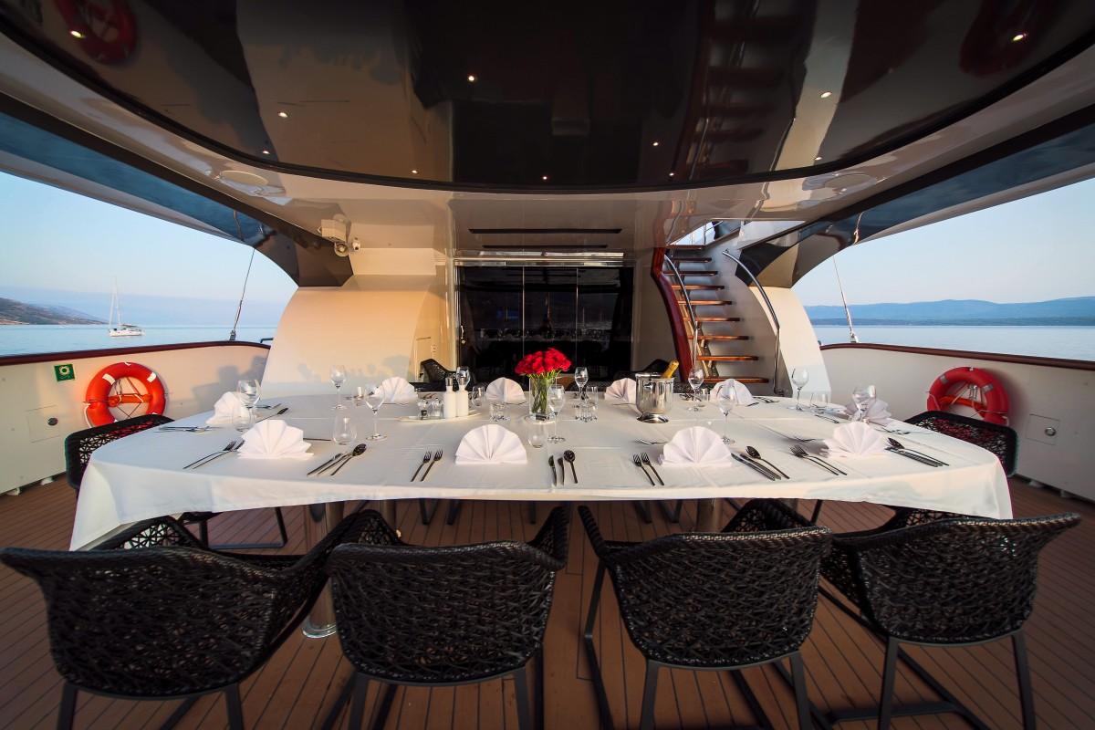 Elegant dining table setup on luxury yacht aft deck with formal place settings