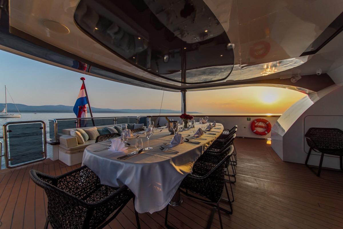 luxury yacht aft deck dining table set for dinner at sunset