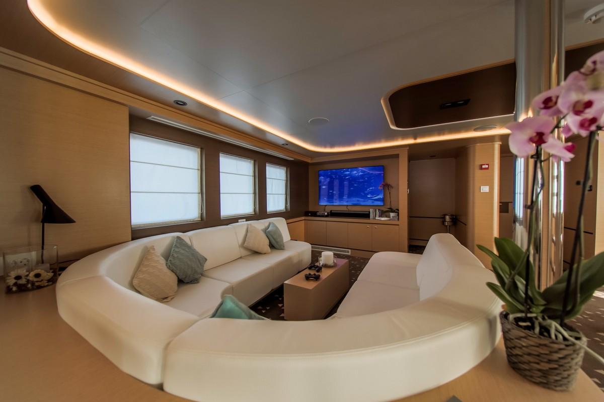 luxury yacht main salon with curved white seating and entertainment center