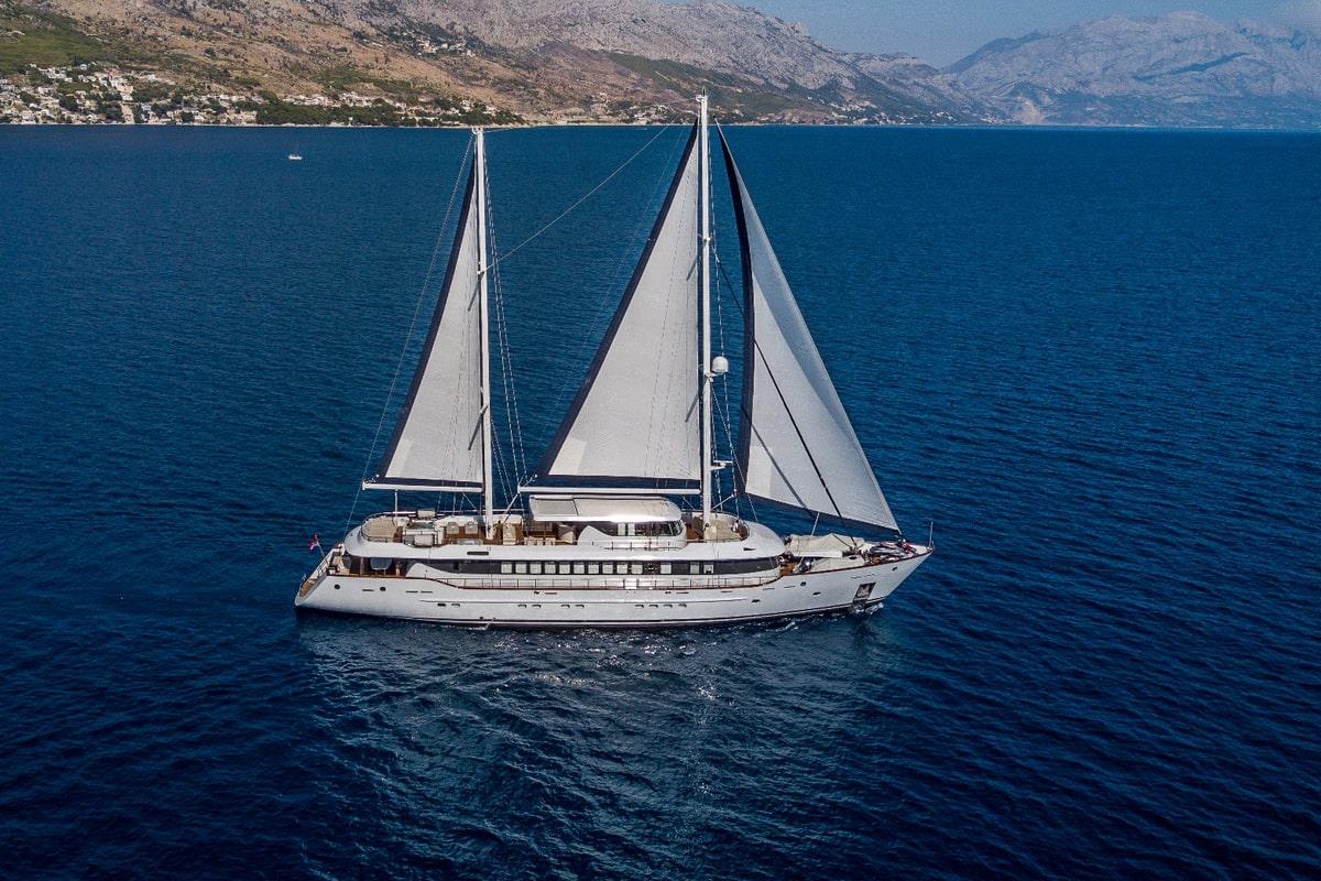 Aerial view of white luxury sailing yacht with white sails on blue water