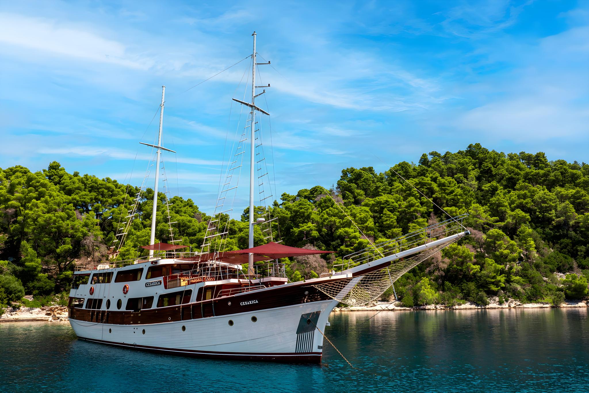 Wooden gulet yacht Cesarica anchored in turquoise Mediterranean bay surrounded by forest
