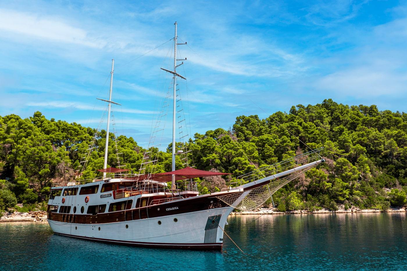 Wooden gulet yacht Cesarica anchored in turquoise Mediterranean bay surrounded by forest