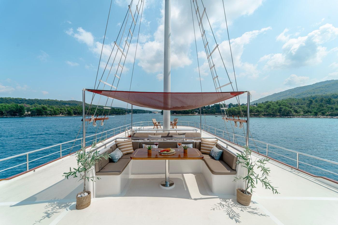 Gulet forward deck with U-shaped seating, wooden table and fabric shade canopy