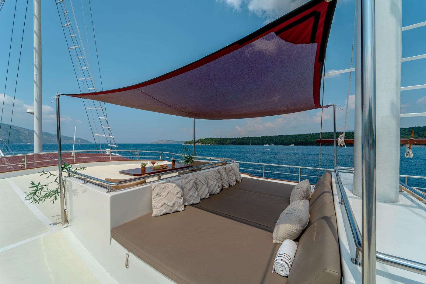 luxury yacht deck seating area with burgundy shade sail and coastal views