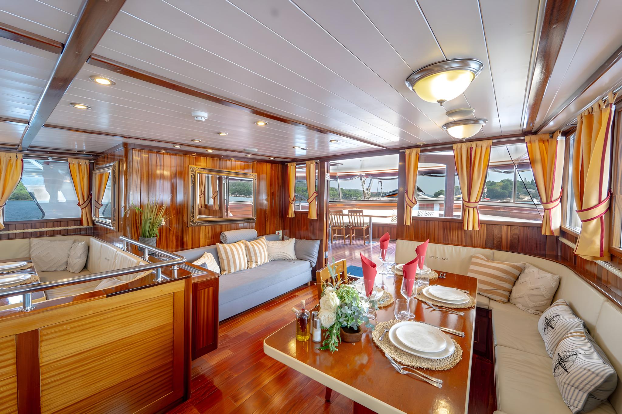 Elegant yacht salon with wood paneling, U-shaped seating, formal dining table