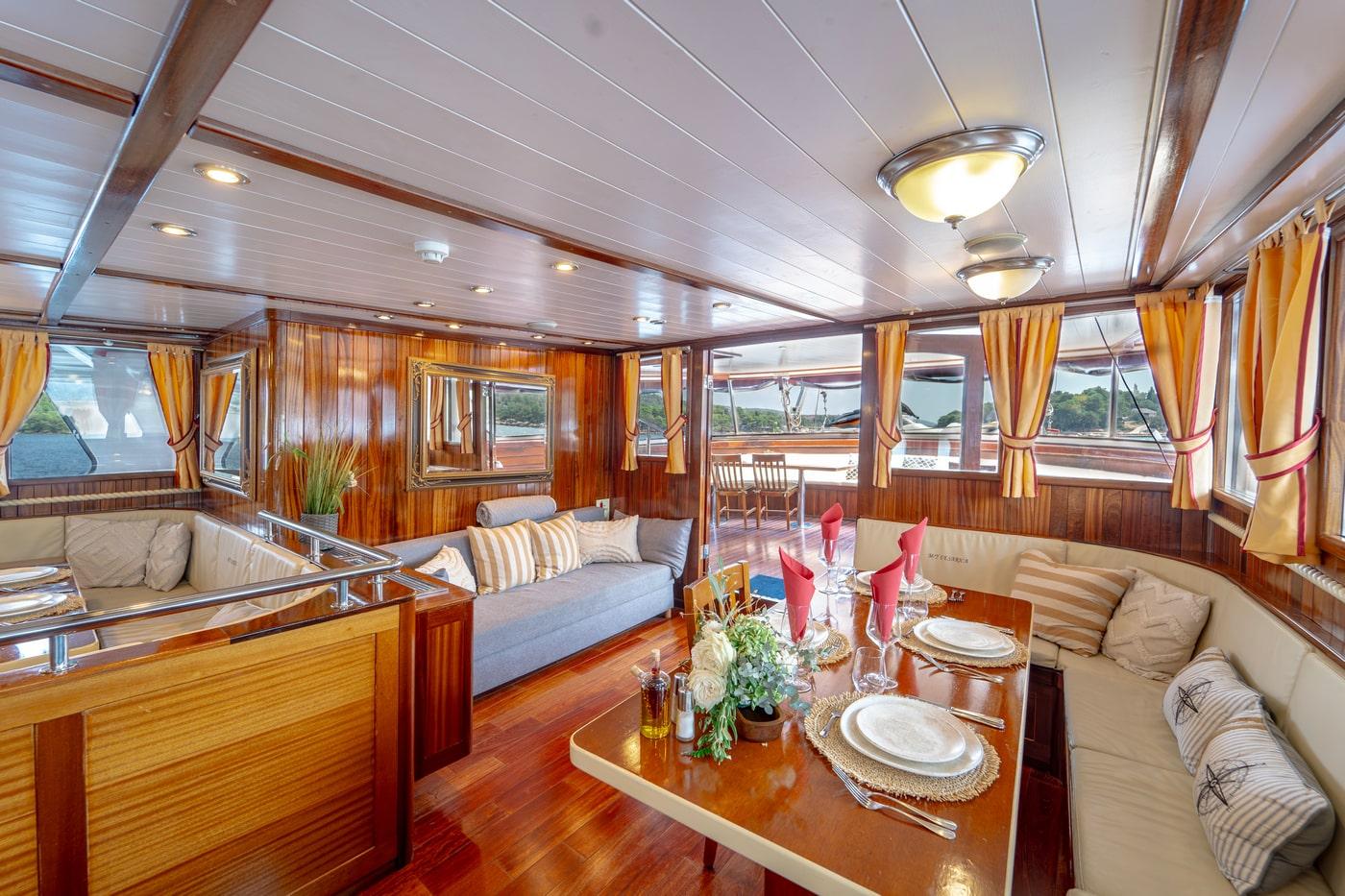 Elegant yacht salon with wood paneling, U-shaped seating, formal dining table