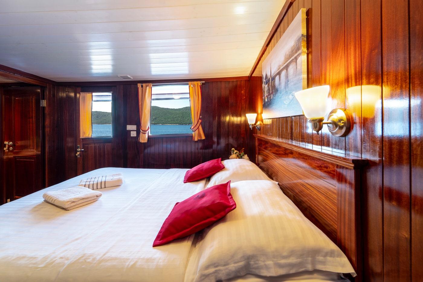 Elegant yacht guest cabin with mahogany wood paneling and ocean view portholes