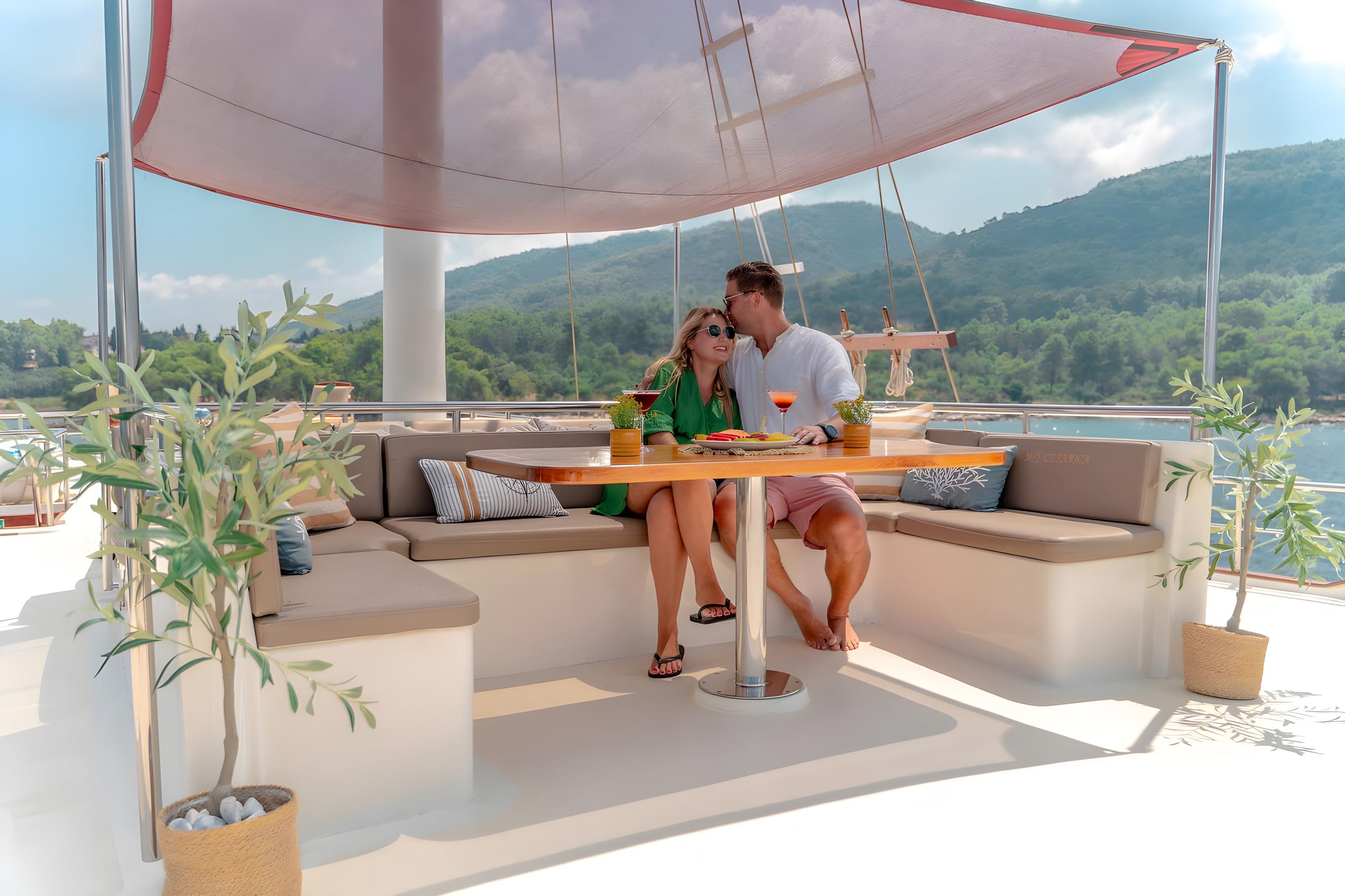 couple enjoying cocktails and dining on luxury yacht aft deck seating area