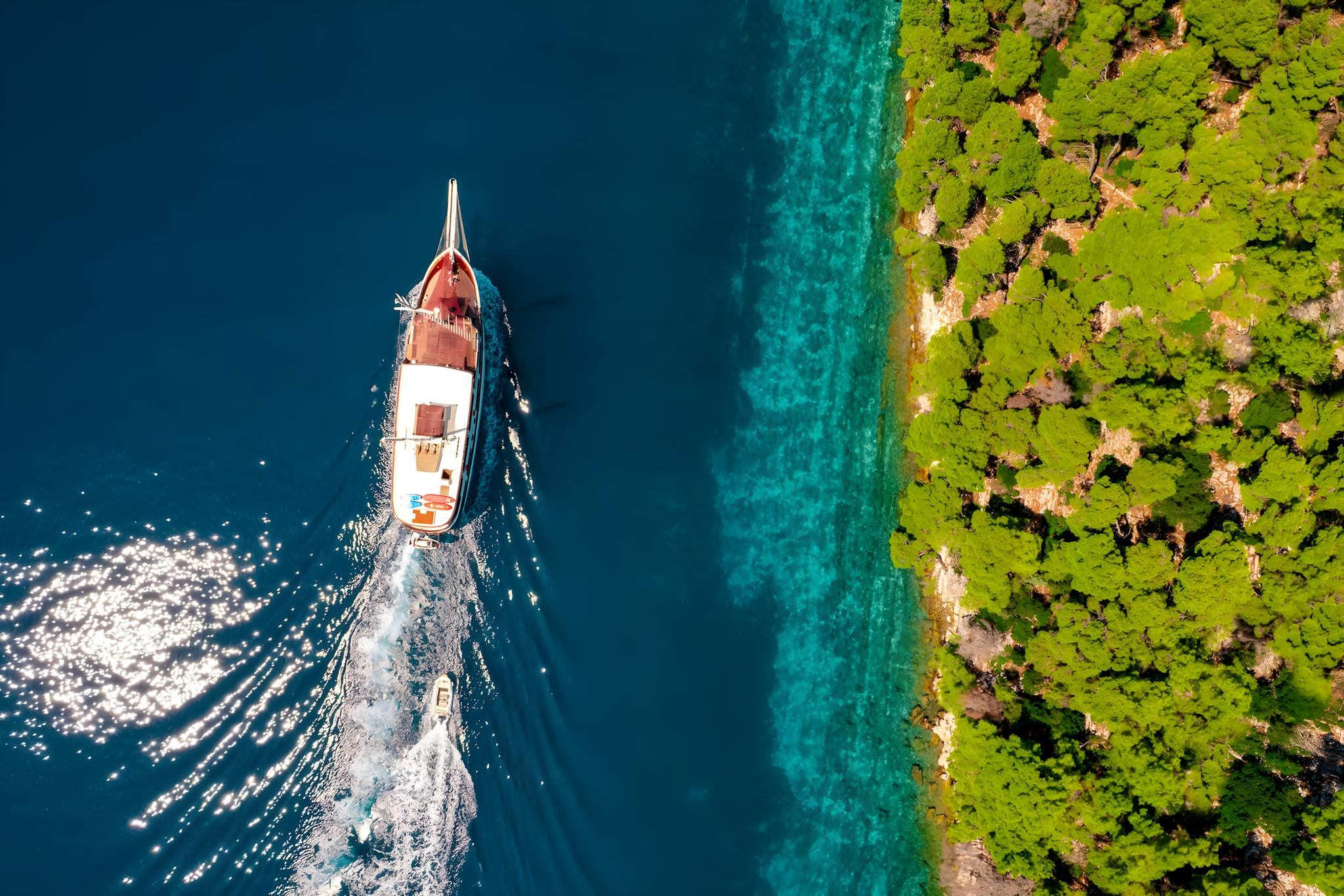 aerial view luxury yacht anchored crystal clear turquoise waters Mediterranean coast