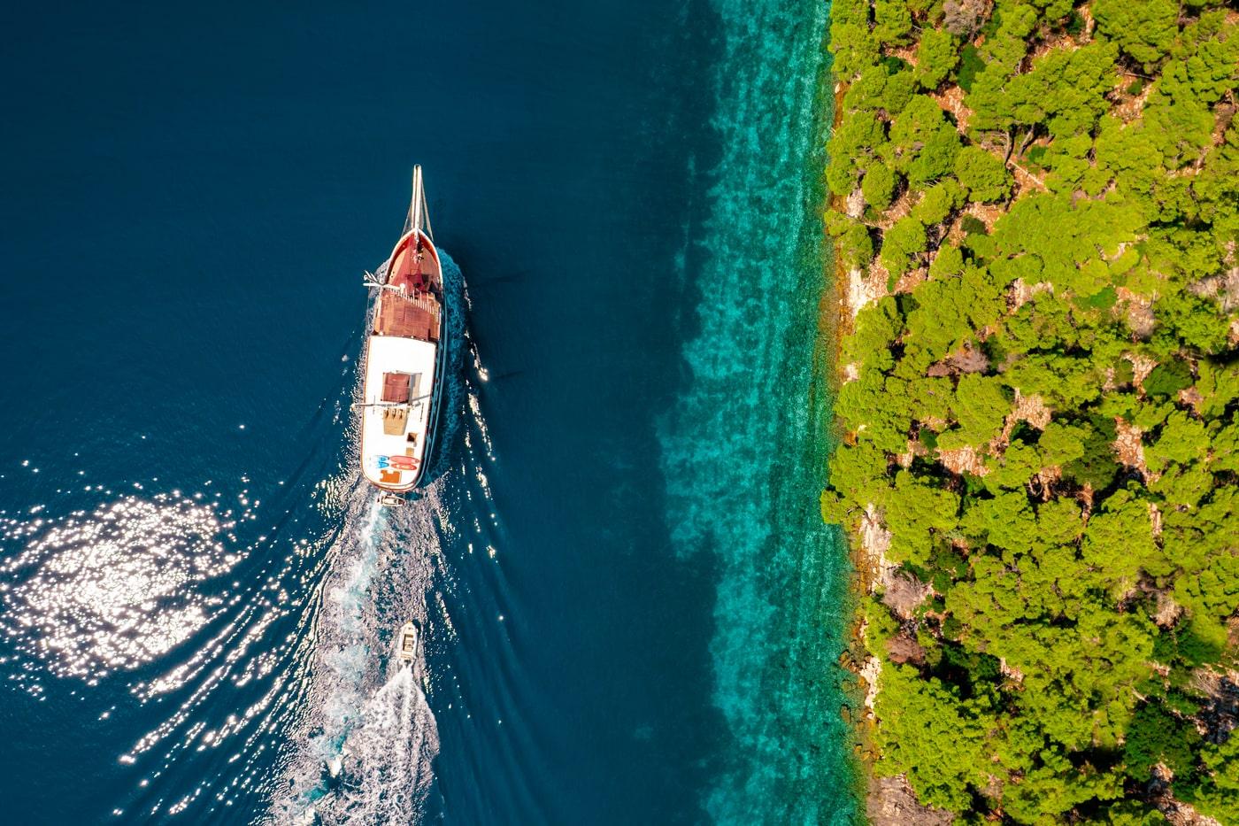 aerial view luxury yacht anchored crystal clear turquoise waters Mediterranean coast