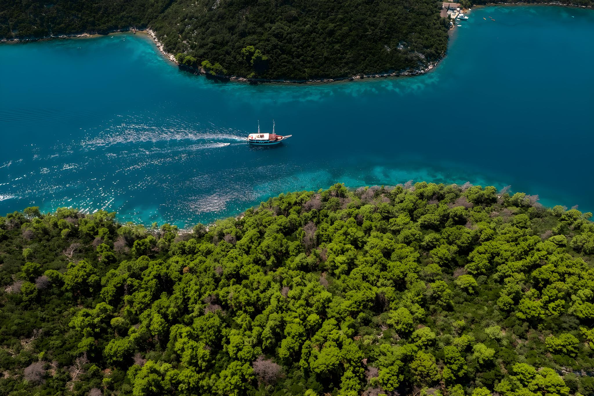 Aerial view of traditional wooden gulet yacht sailing in pristine turquoise bay