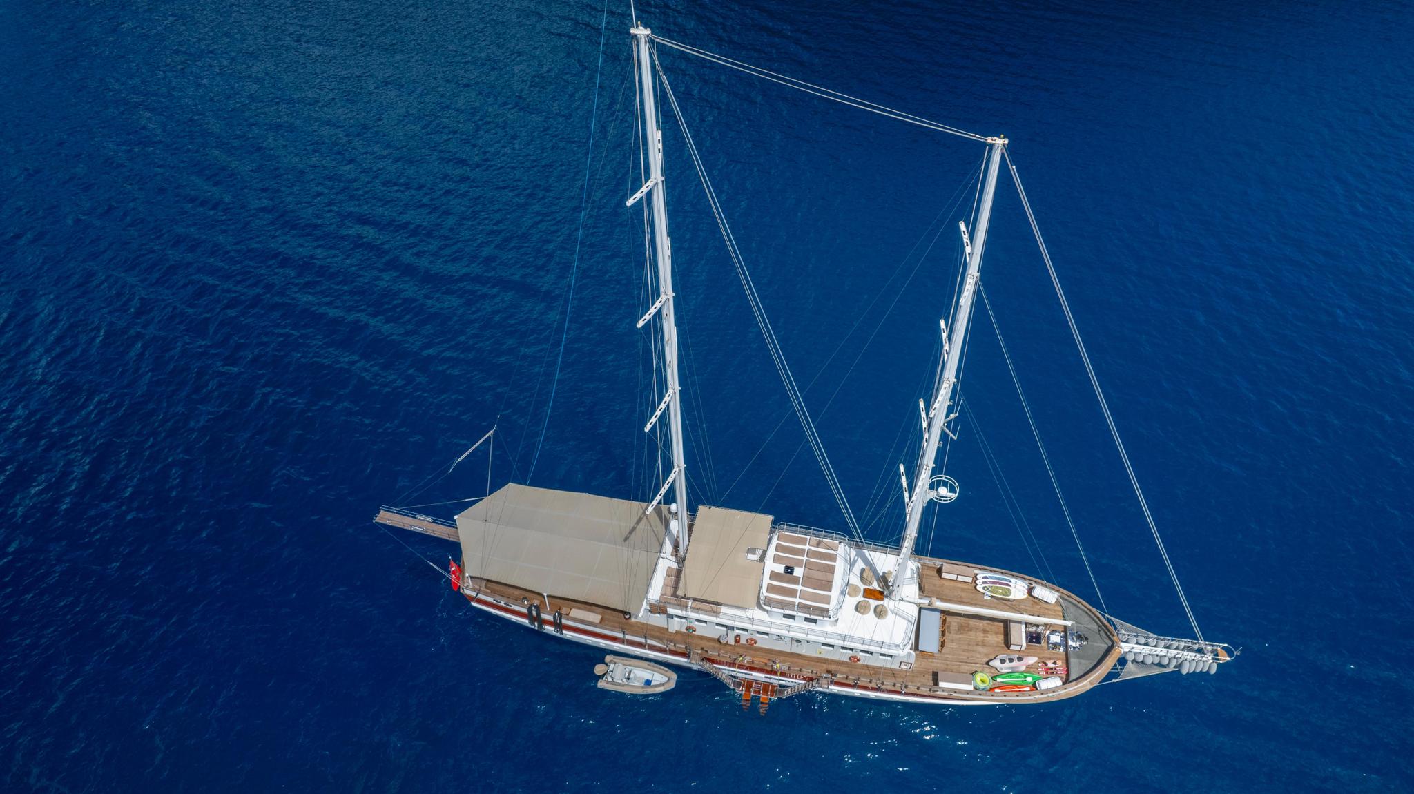 aerial drone shot of white traditional gulet with two masts anchored in deep blue Mediterranean waters