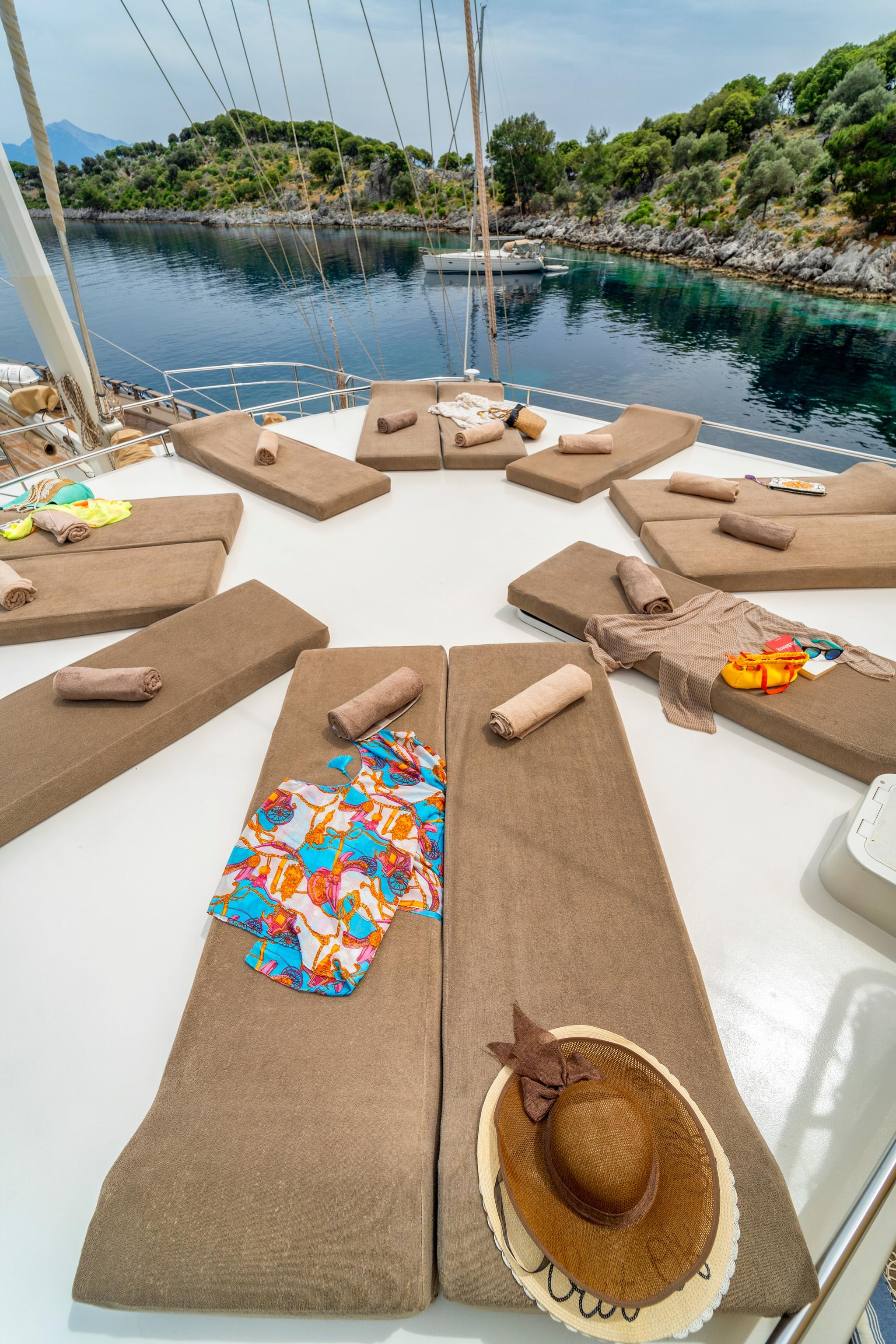 bow sun deck with beige cushioned loungers arranged around mast in secluded bay