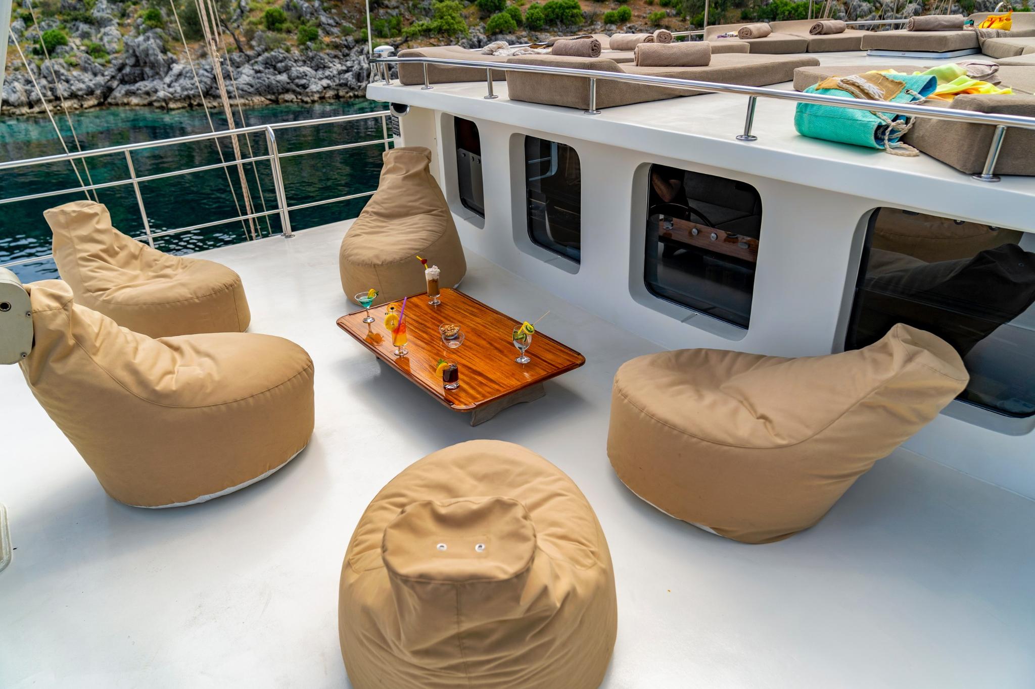 yacht aft deck lounge with beige bean bag chairs around wooden coffee table