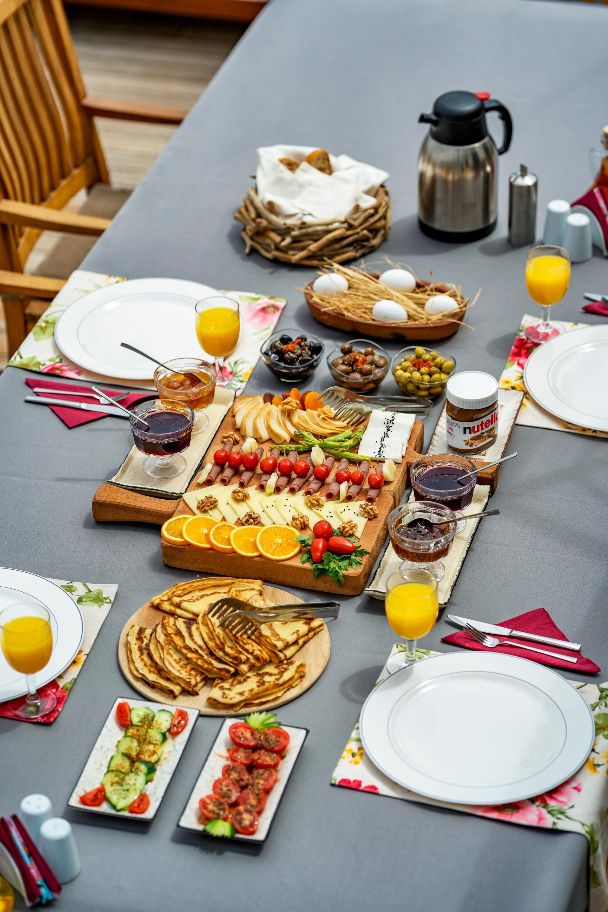 yacht breakfast table with cheese board, pancakes, fresh fruits and orange juice