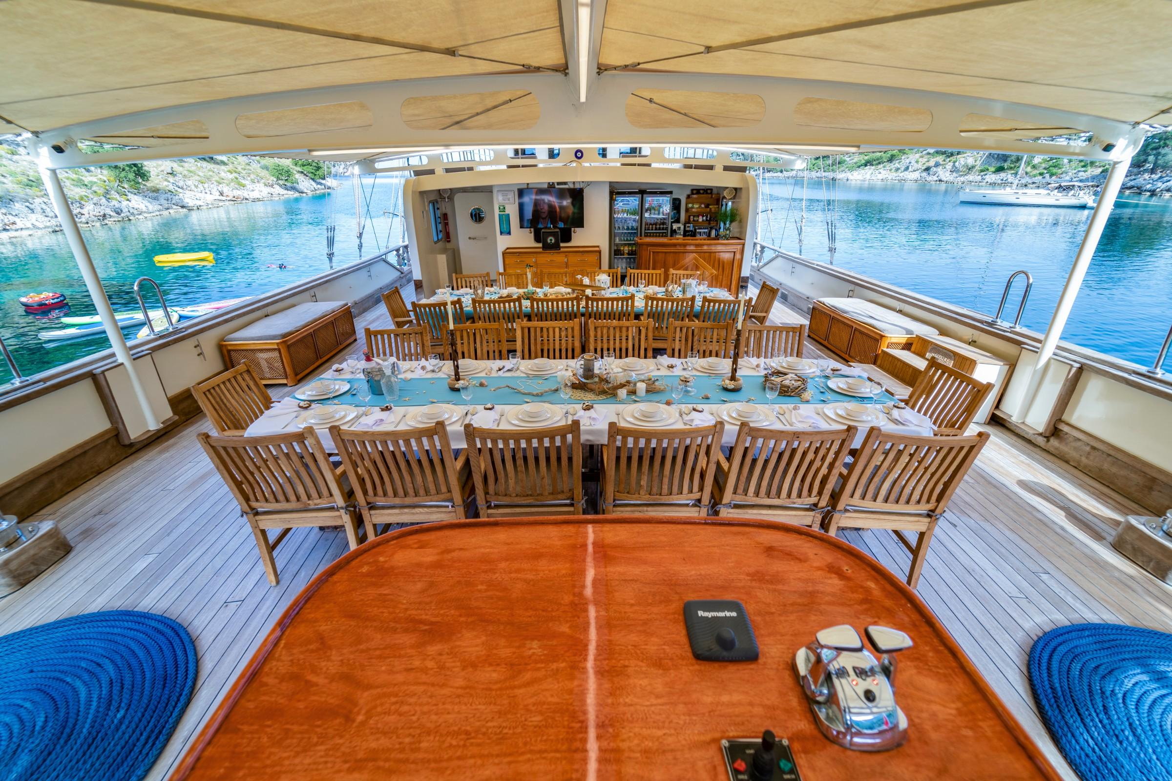 gulet aft deck with formal dining table set for guests under shade canopy