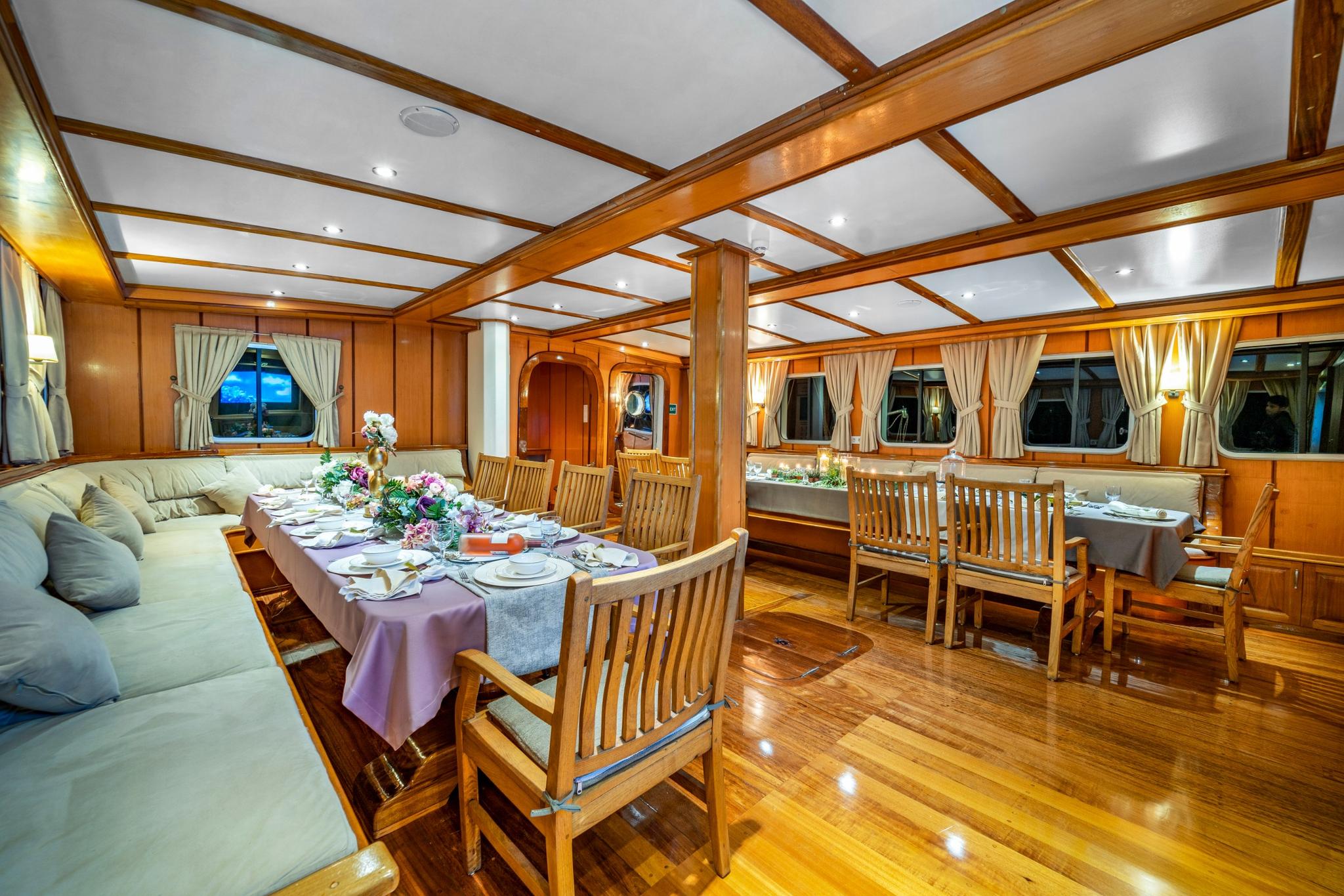 yacht salon interior with formal dining table, wooden chairs, and panoramic windows