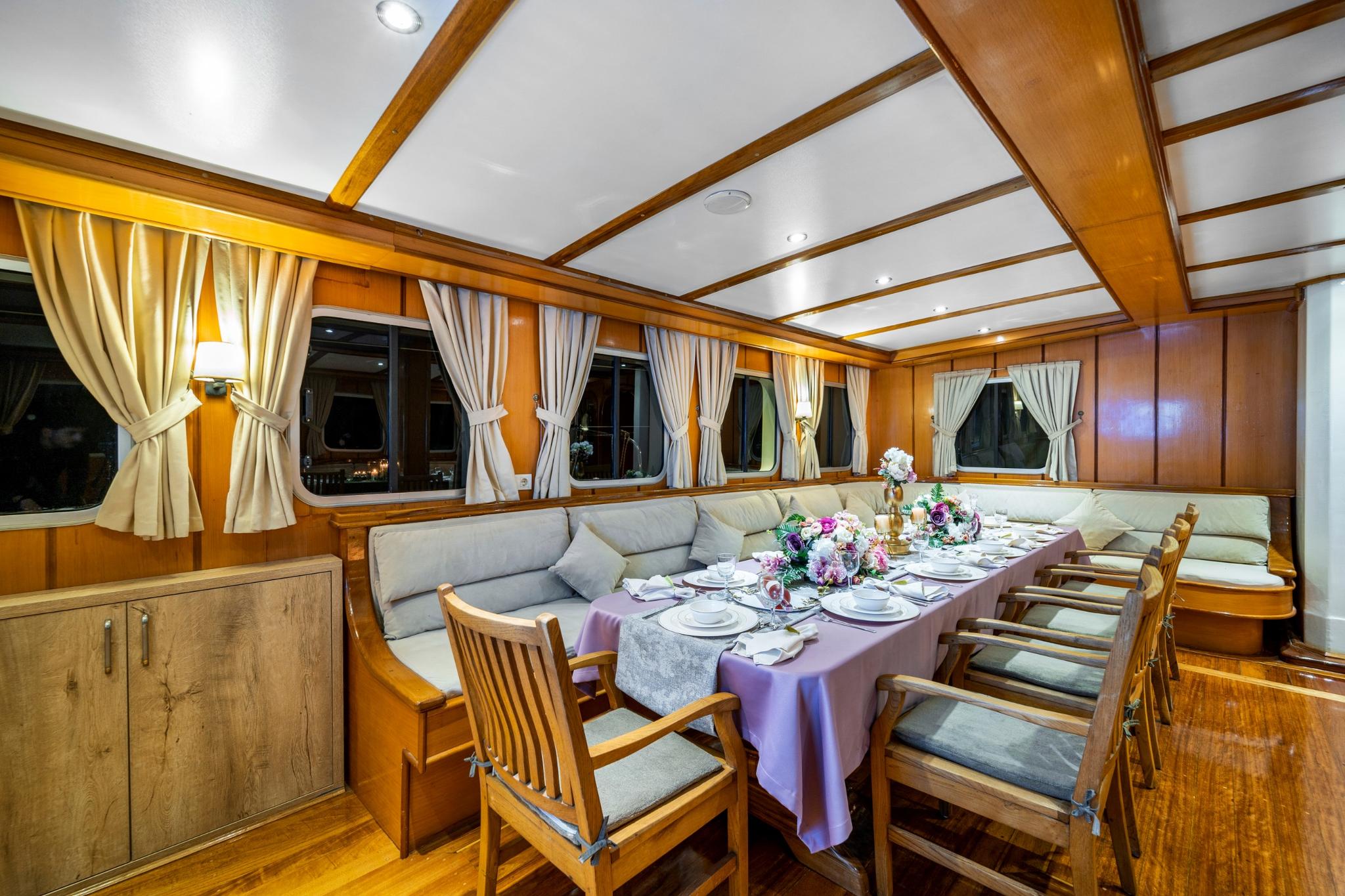 yacht dining salon with formal table setting, built-in seating and panoramic windows