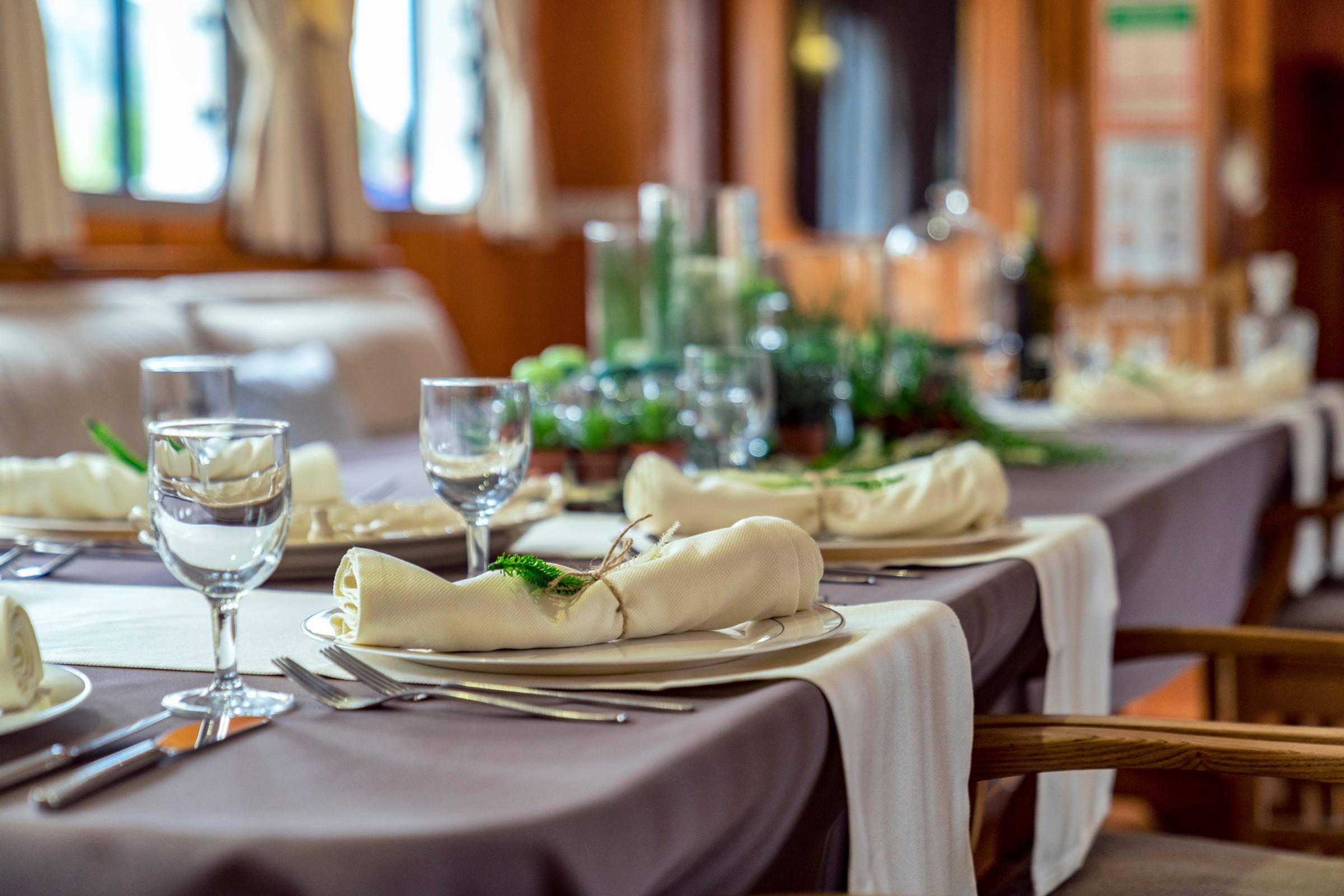 elegant yacht dining table with wine glasses, place settings and cream napkins
