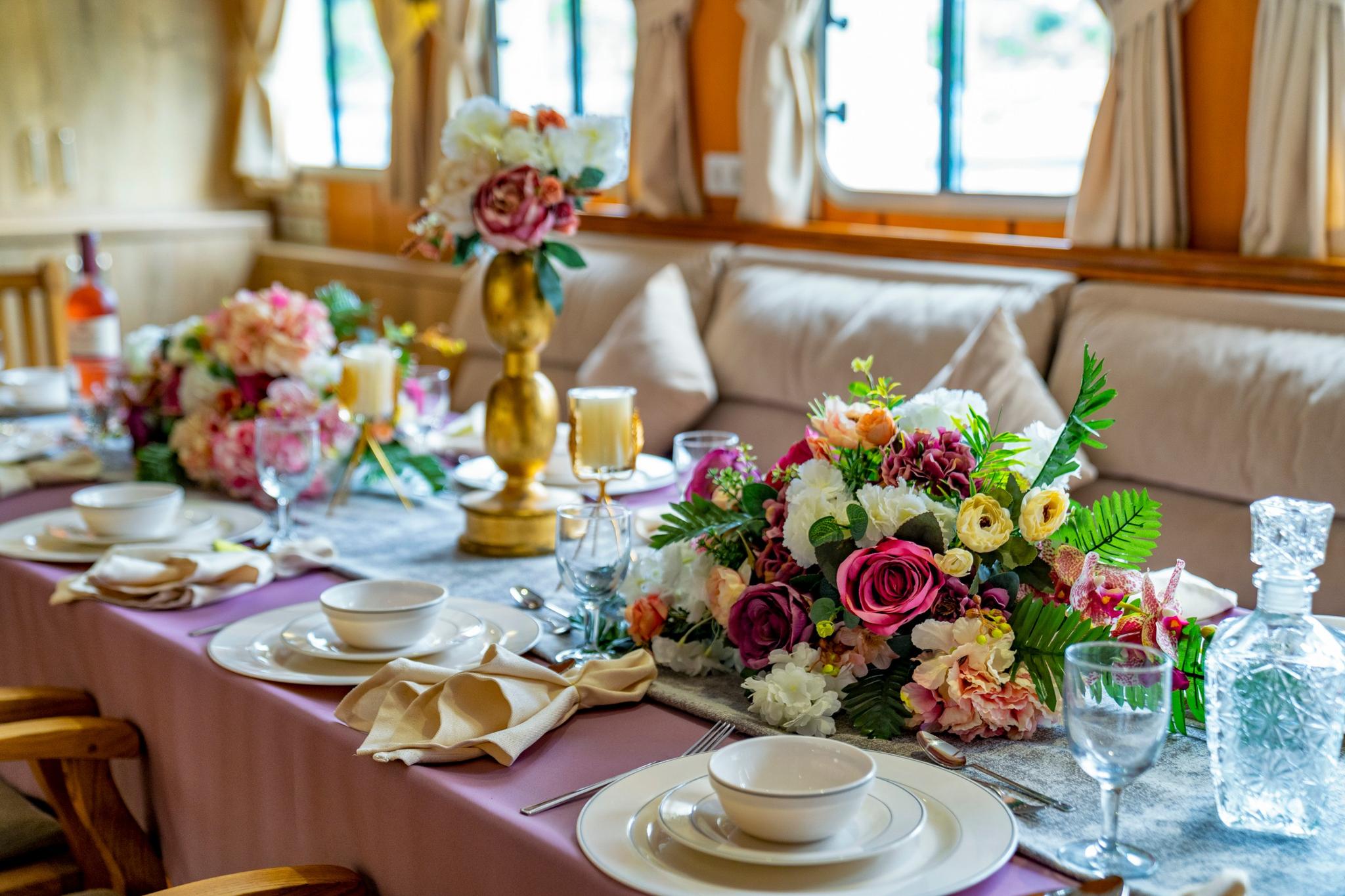 elegant yacht dining table with fine china, crystal glasses and colorful floral centerpieces