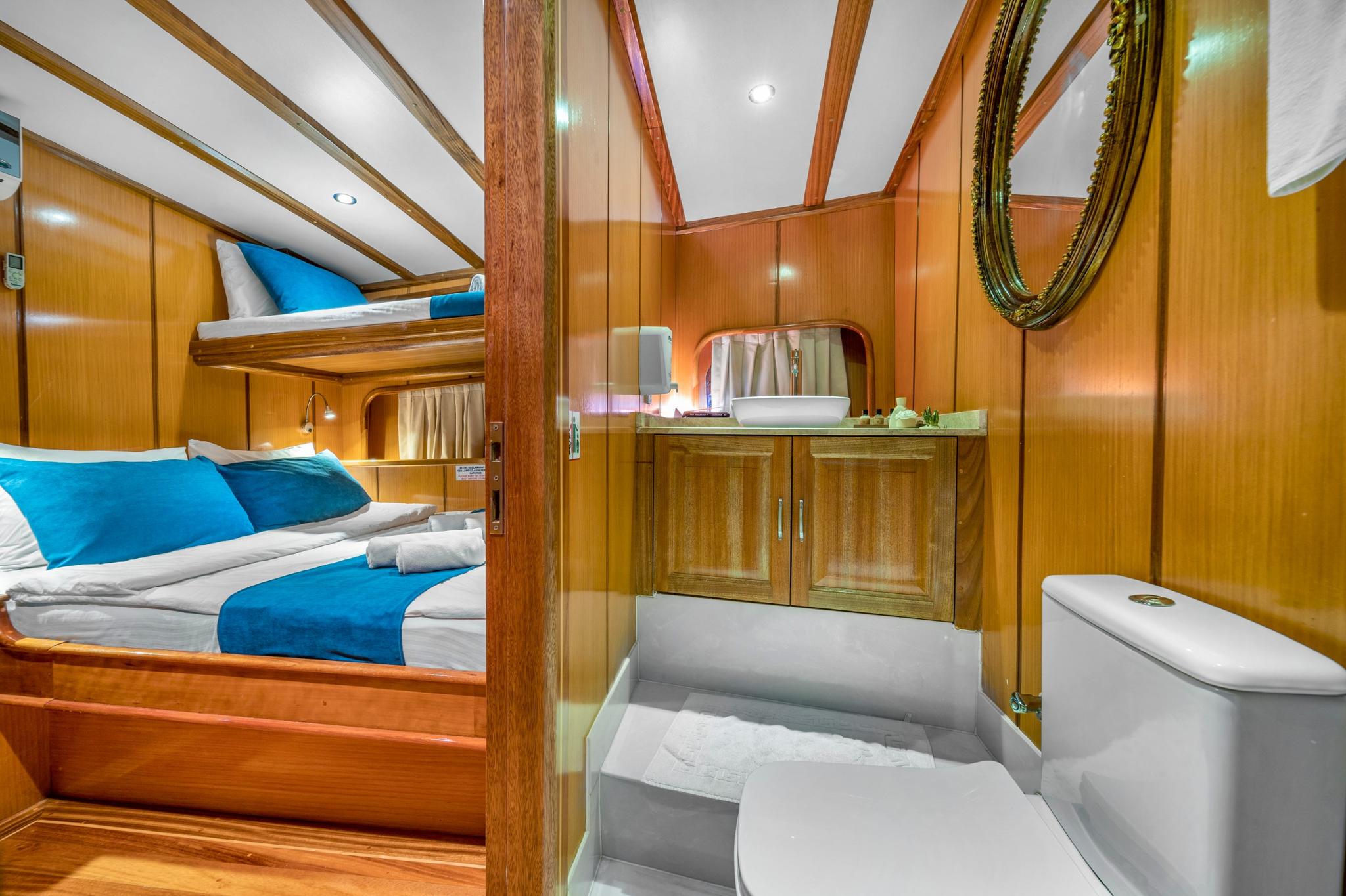 yacht guest cabin featuring wooden bunk beds with blue bedding and private ensuite bathroom