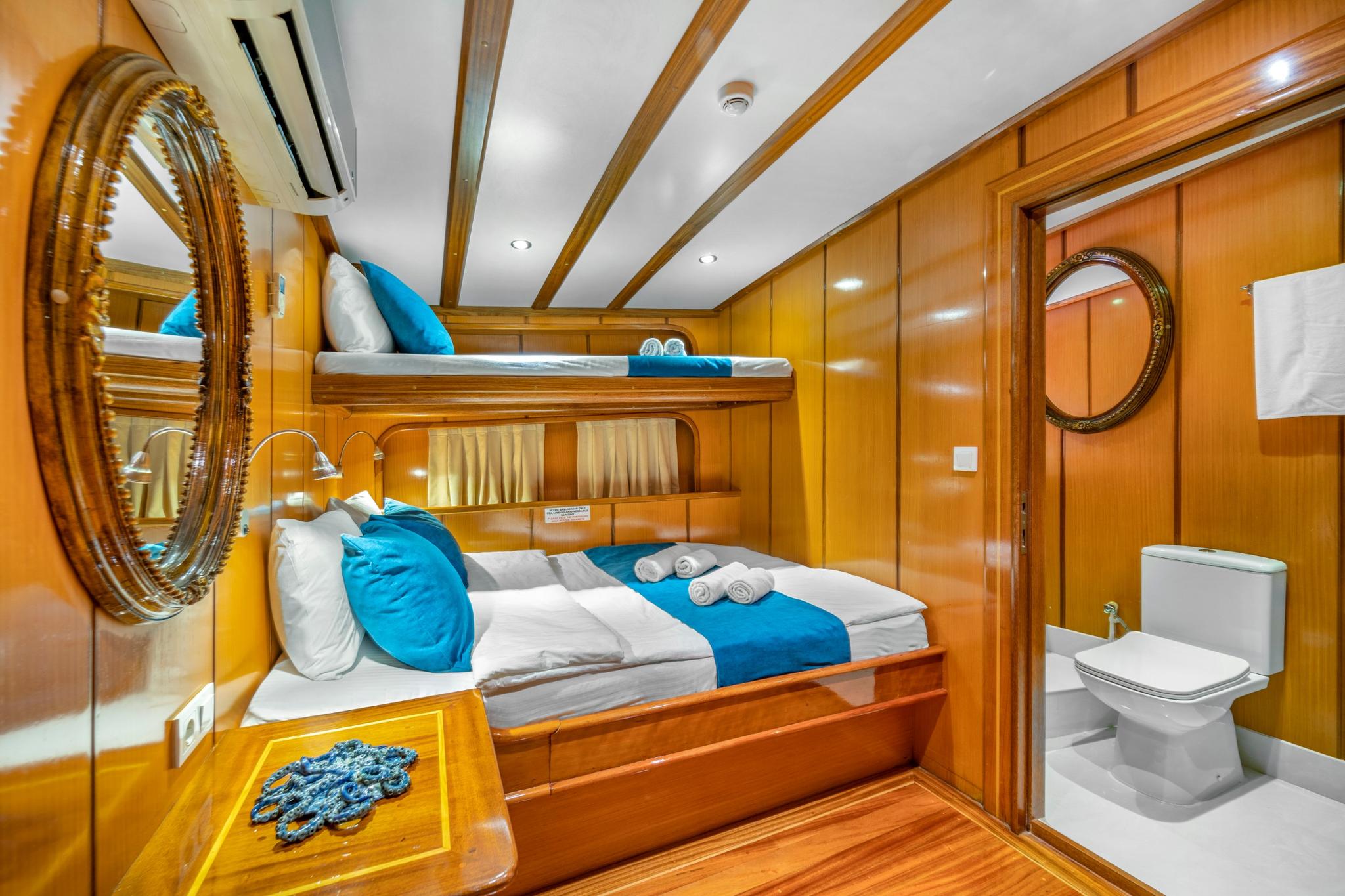 yacht guest cabin featuring bunk beds with blue bedding and integrated bathroom with toilet
