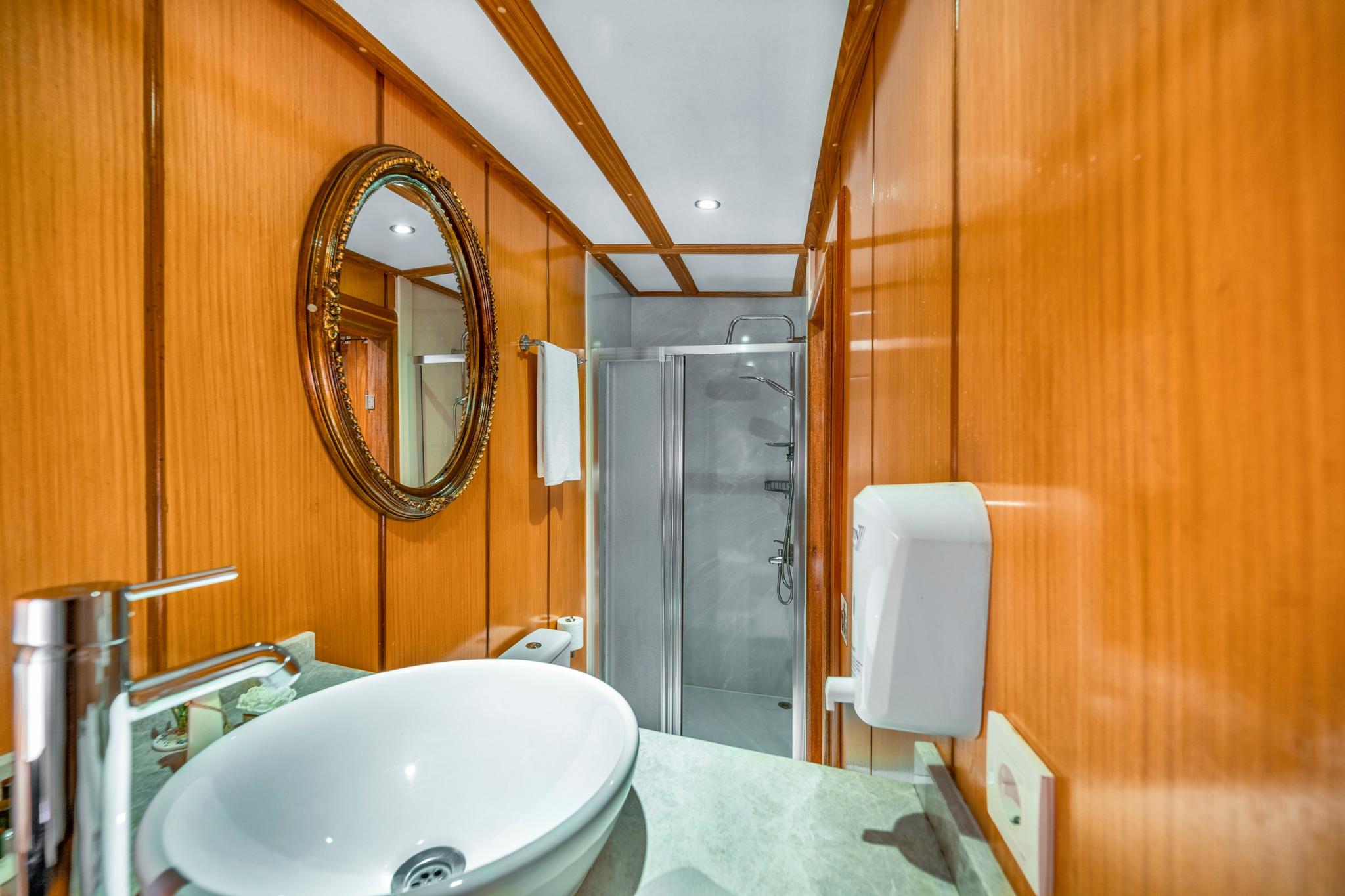 luxury yacht bathroom with wood paneling vessel sink marble countertop glass shower