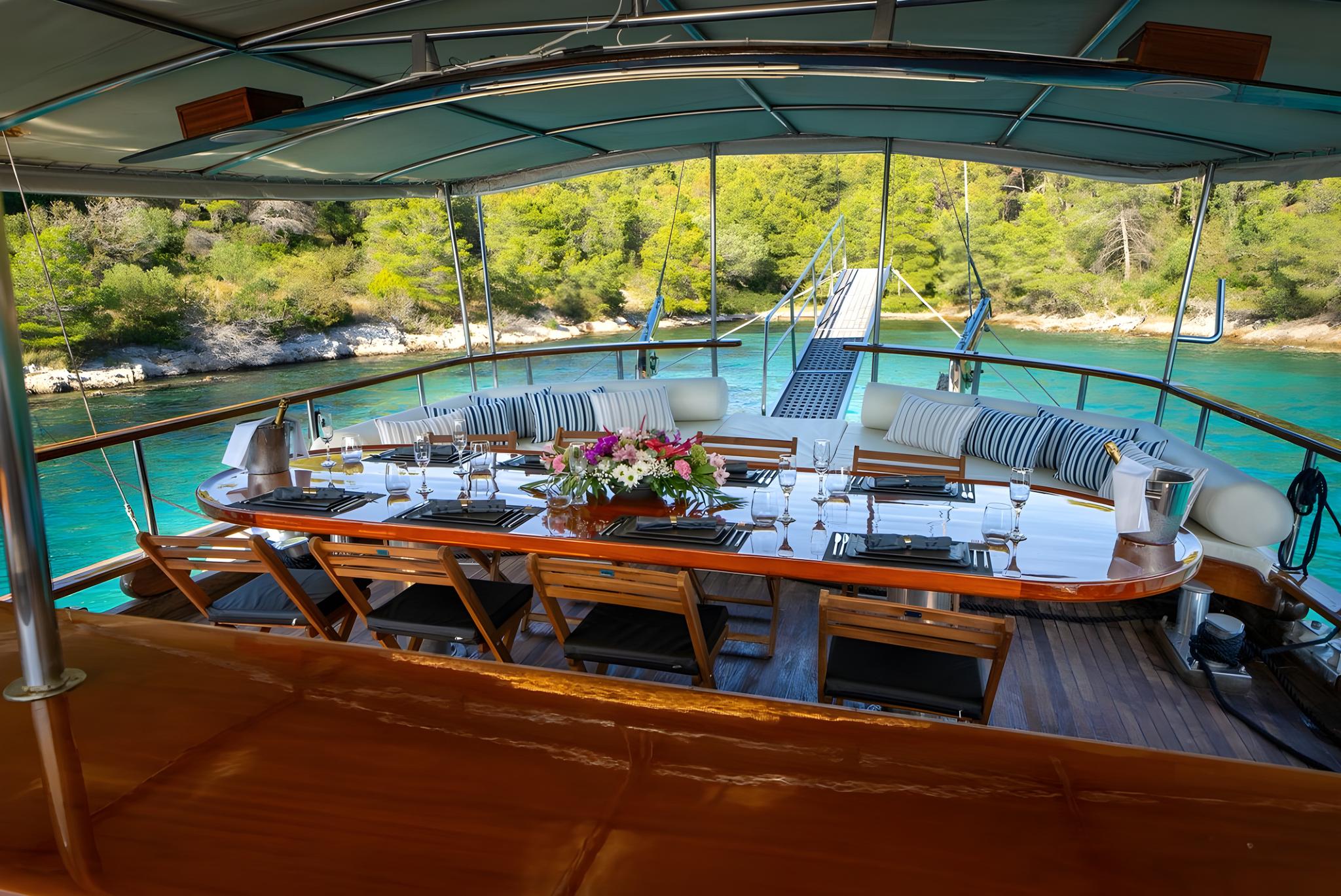 luxury gulet aft deck dining area with curved banquette and turquoise bay