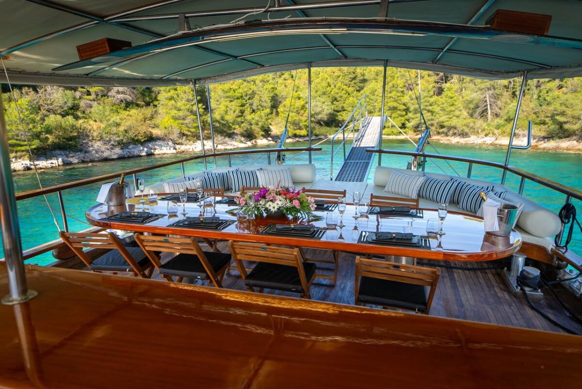 luxury gulet aft deck dining area with curved banquette and turquoise bay