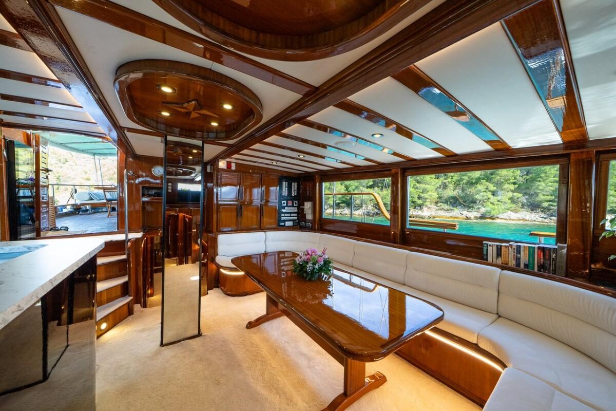 Elegant yacht salon interior with curved white leather seating and rich wood trim