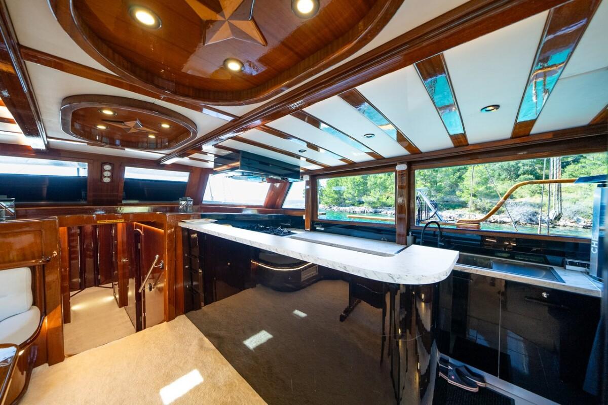 Elegant yacht salon interior featuring marble bar counter and carved wooden ceiling