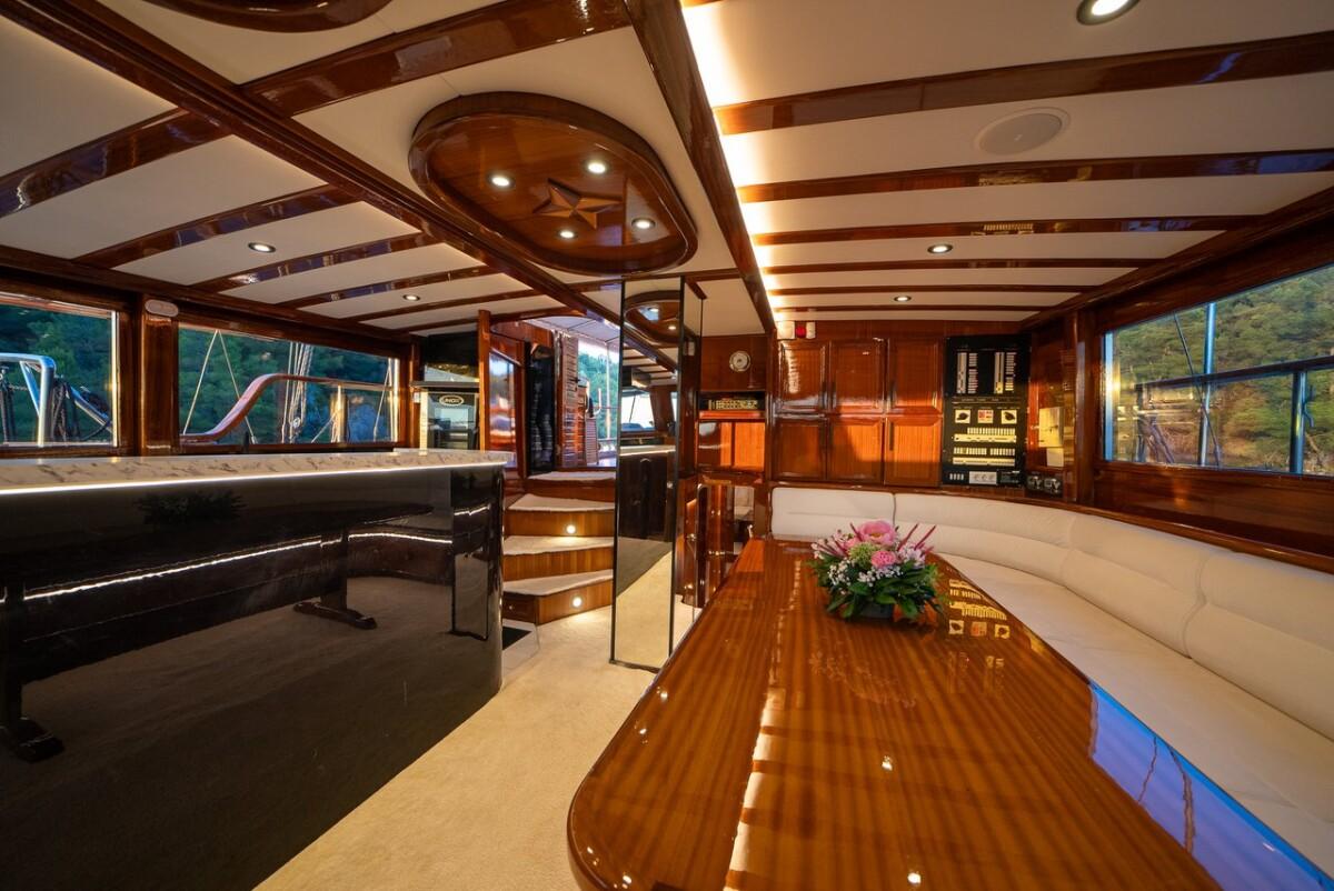 Elegant yacht salon interior with mahogany wood paneling and curved dining table