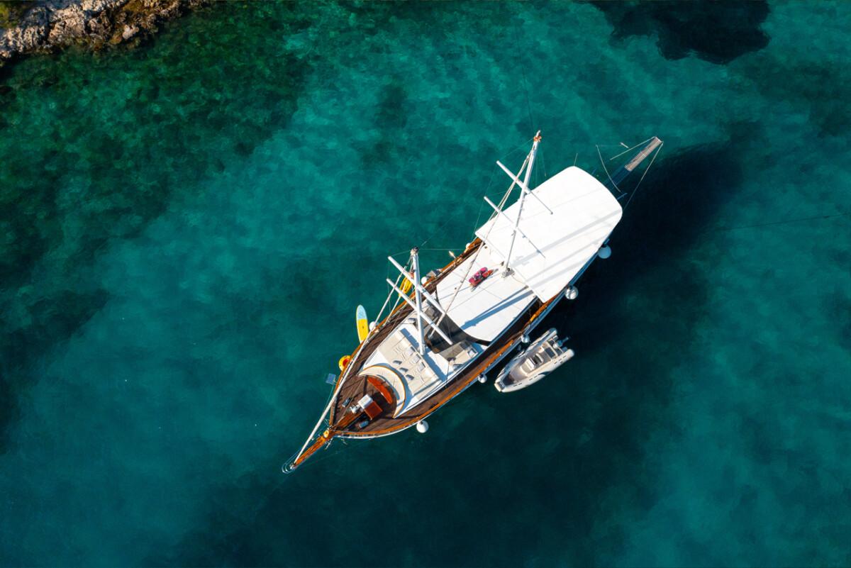 Aerial view of luxury wooden gulet yacht anchored in crystal clear turquoise waters