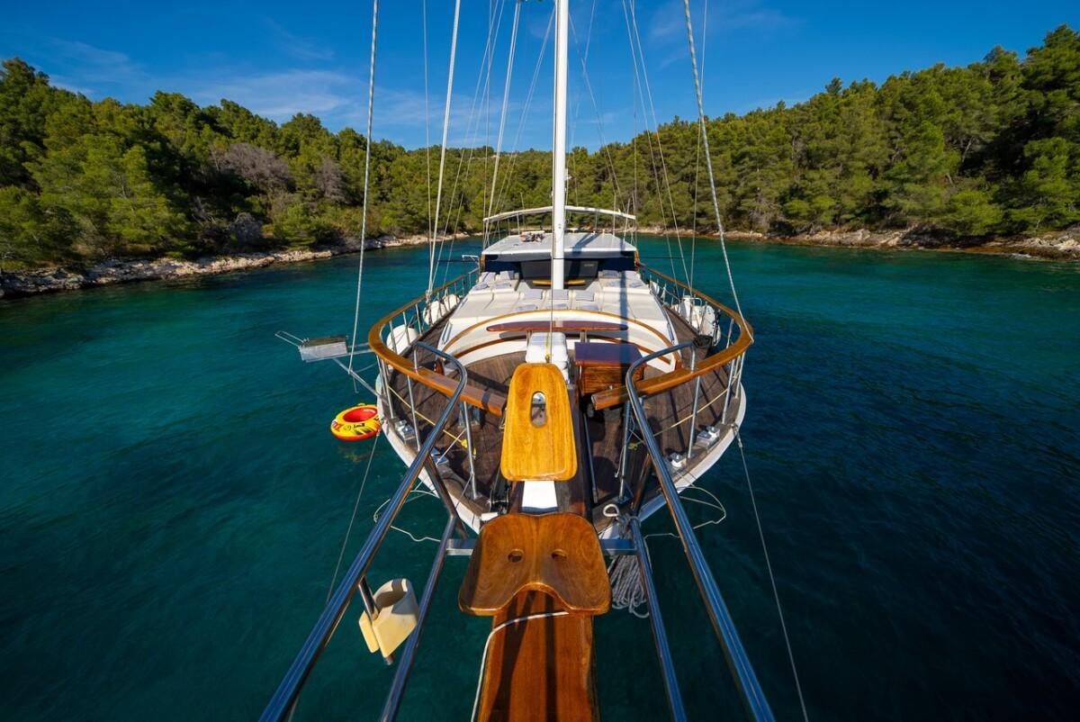 Aerial view of traditional wooden gulet yacht anchored in pristine turquoise Mediterranean cove