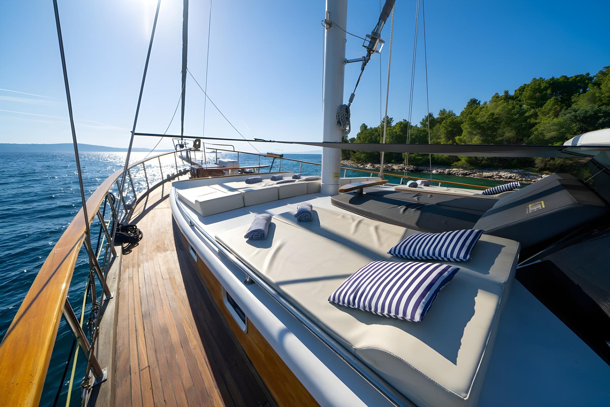 Luxury yacht foredeck with white sun cushions, striped pillows, teak decking