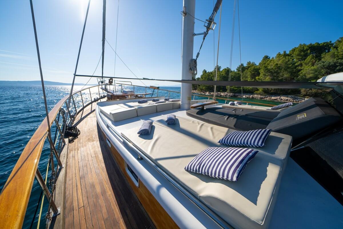Luxury yacht foredeck with white sun cushions, striped pillows, teak decking