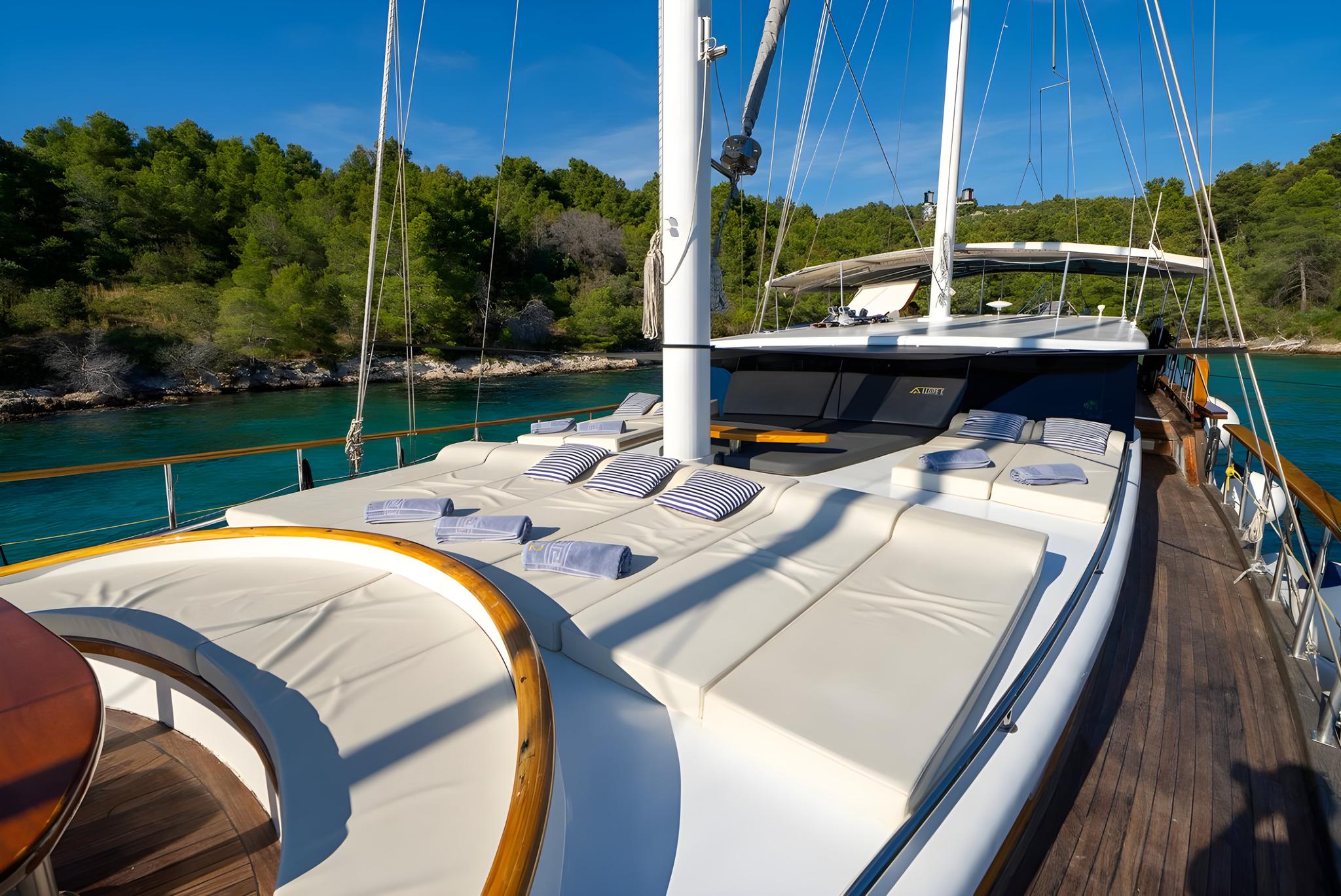 luxury gulet foredeck sunbathing cushions overlooking turquoise Mediterranean bay
