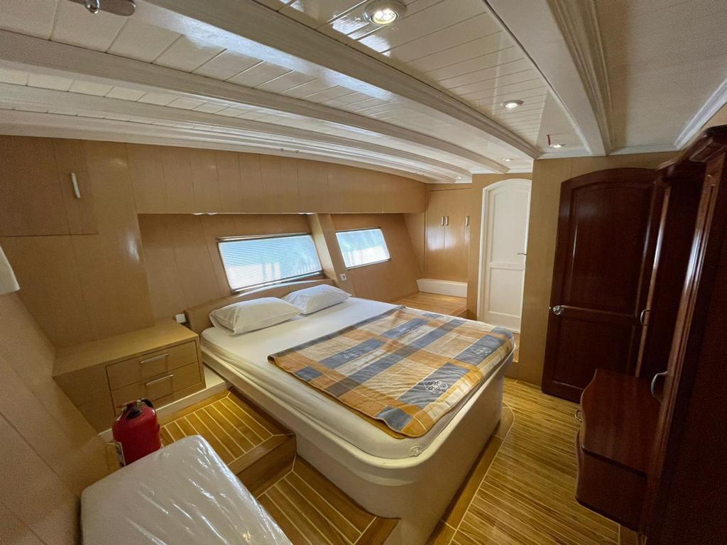 yacht cabin interior with double bed, built-in wardrobes, side windows and teak flooring