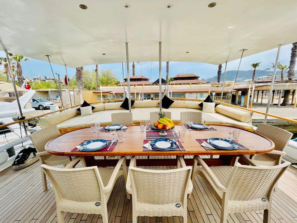 yacht aft deck dining table set for eight guests with wicker chairs