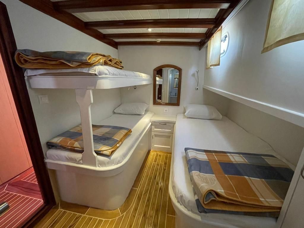 crew cabin interior with white bunk beds, single bed, and teak flooring