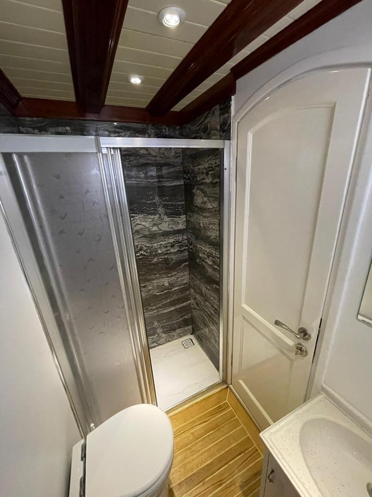yacht bathroom interior showing shower stall with stone-effect walls and white toilet