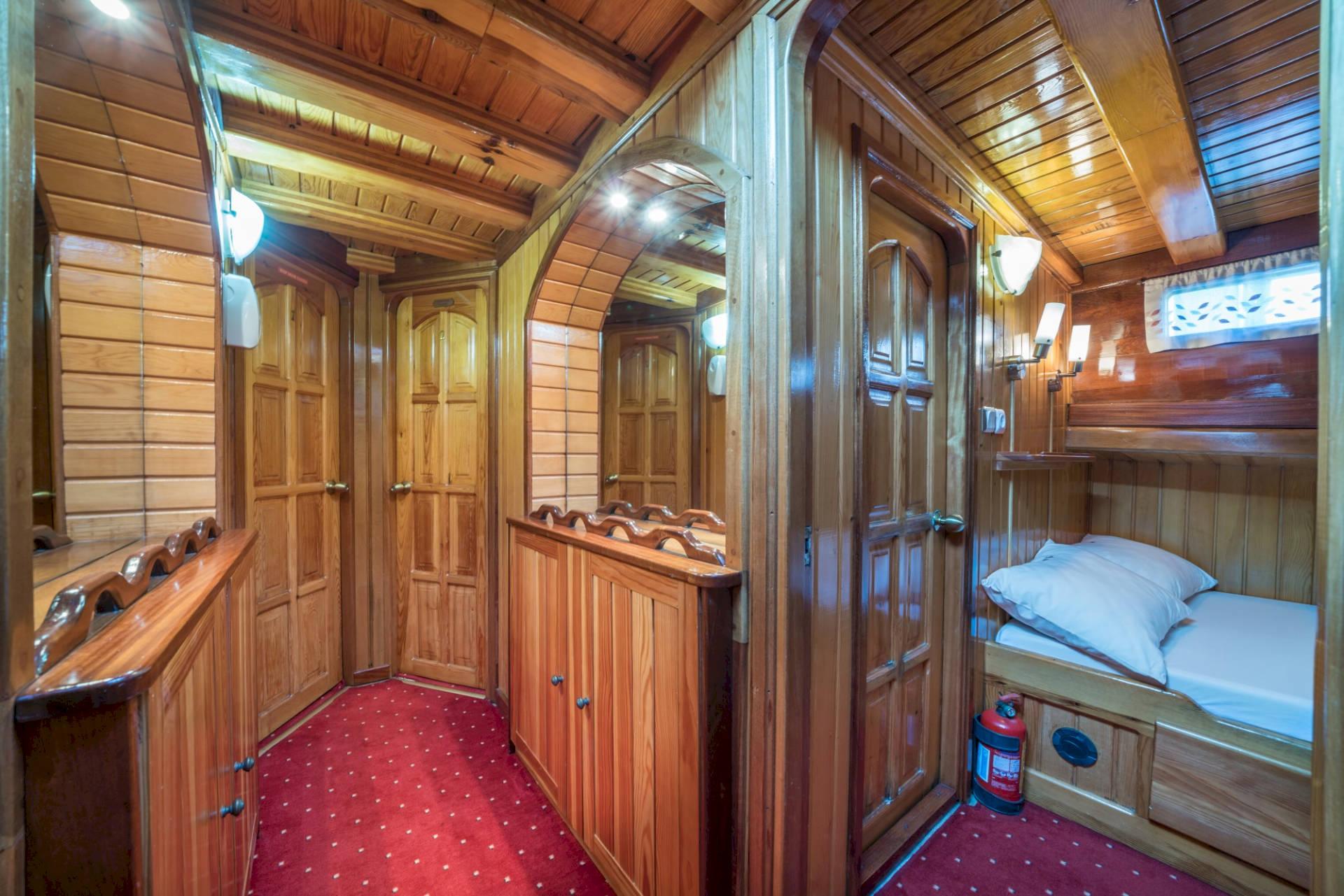 wooden accommodation corridor on traditional gulet with cabin doors and single berth