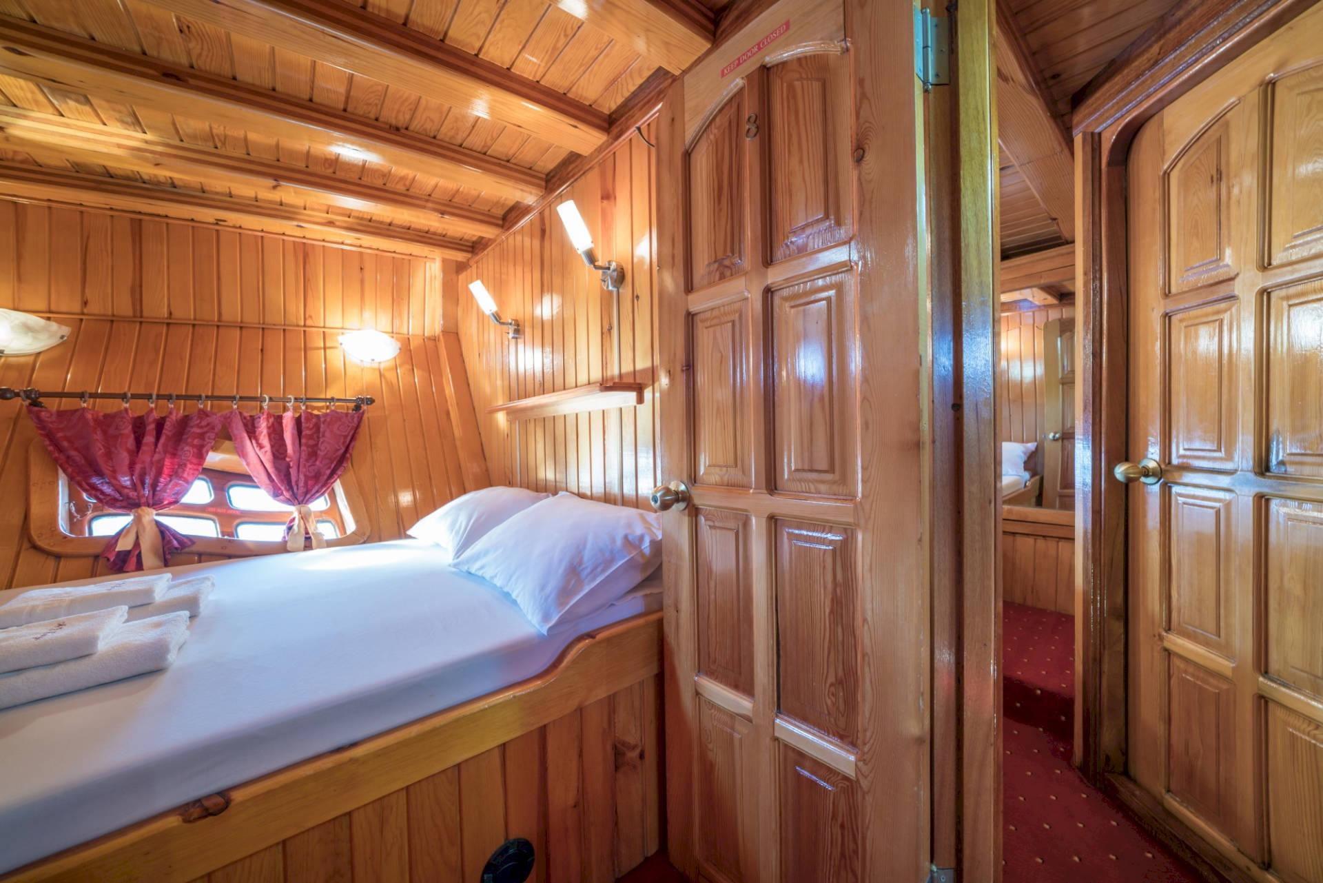 yacht guest cabin featuring single bed, built-in wardrobes, wooden paneling and red carpeting