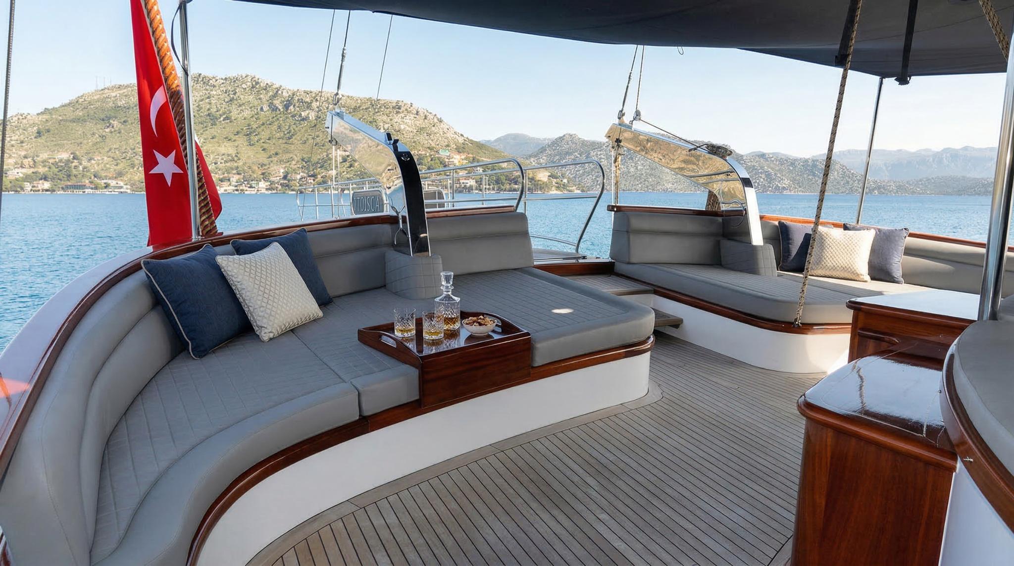 Luxury yacht aft deck with curved grey banquette seating, coffee table and Turkish flag