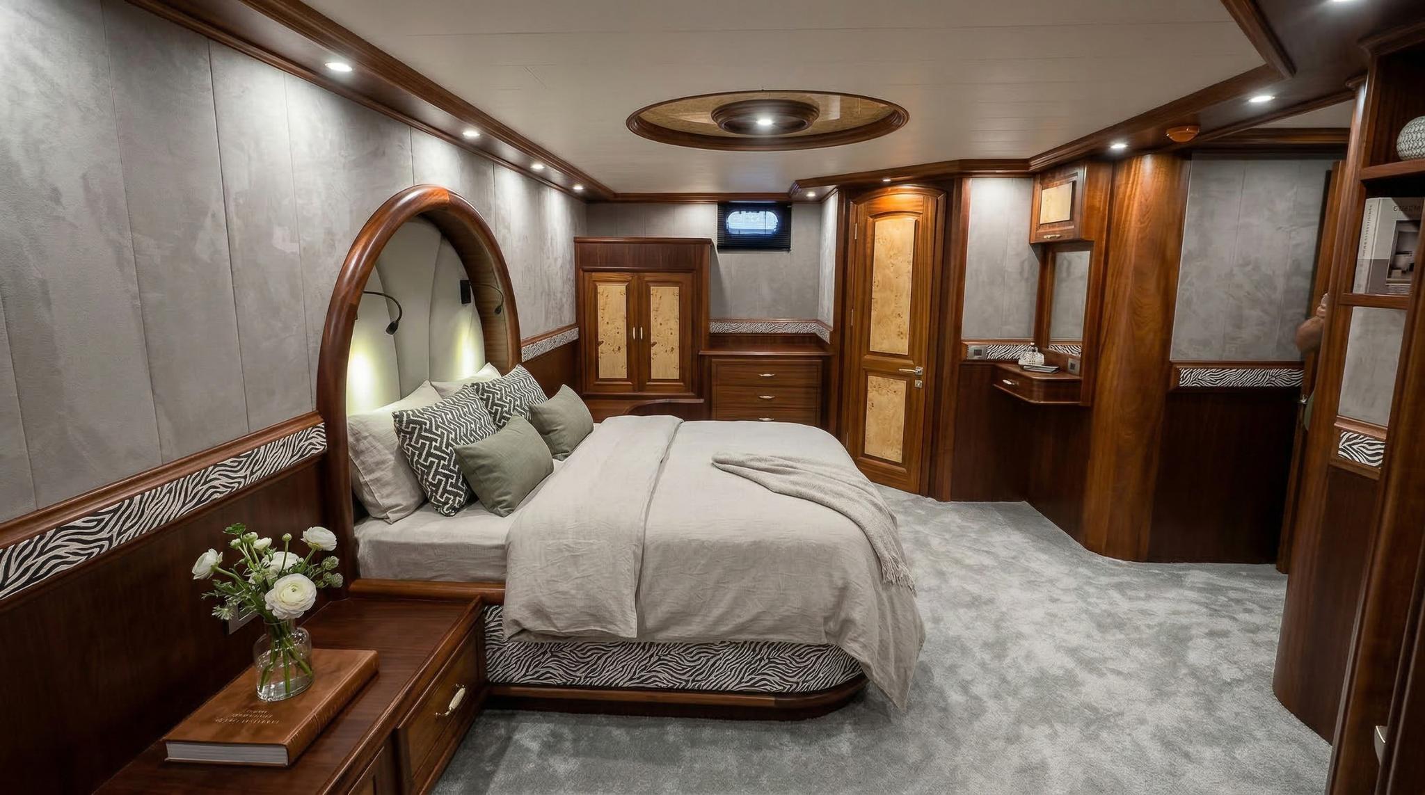 Master cabin interior featuring king bed with curved headboard, built-in wardrobes and vanity area