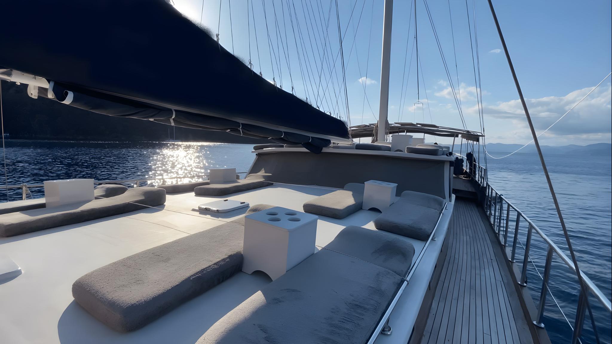 gulet forward deck with curved built-in seating, white coffee table, and teak decking