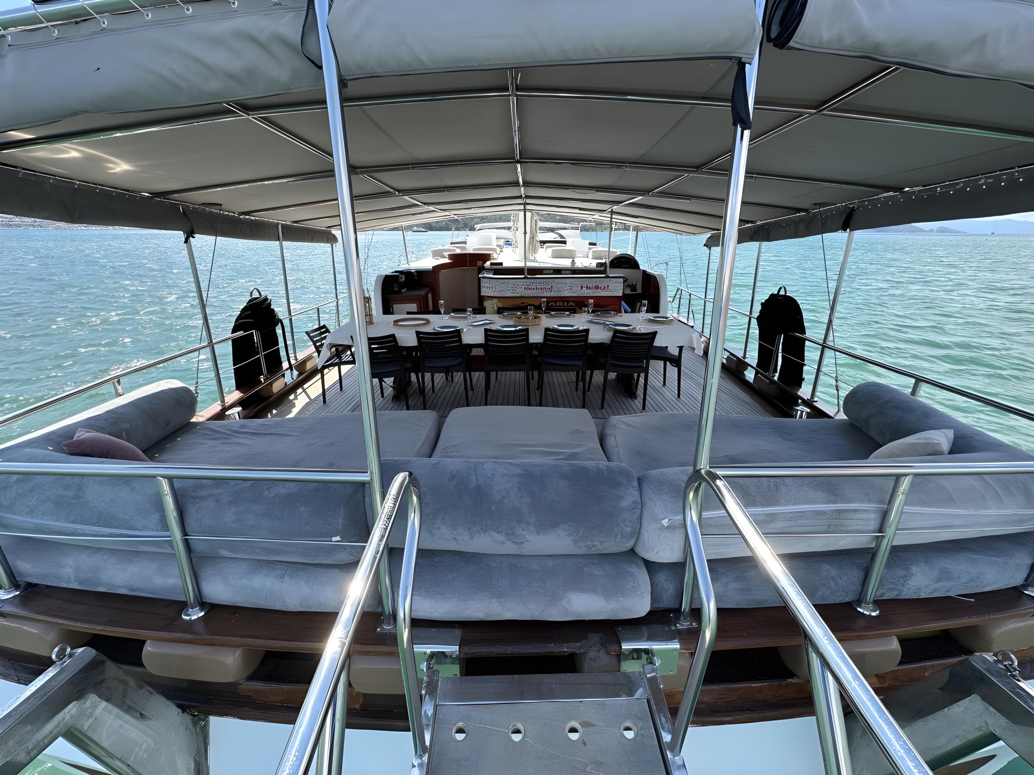 Upper deck lounge area with U-shaped seating, dining table and fabric canopy overhead