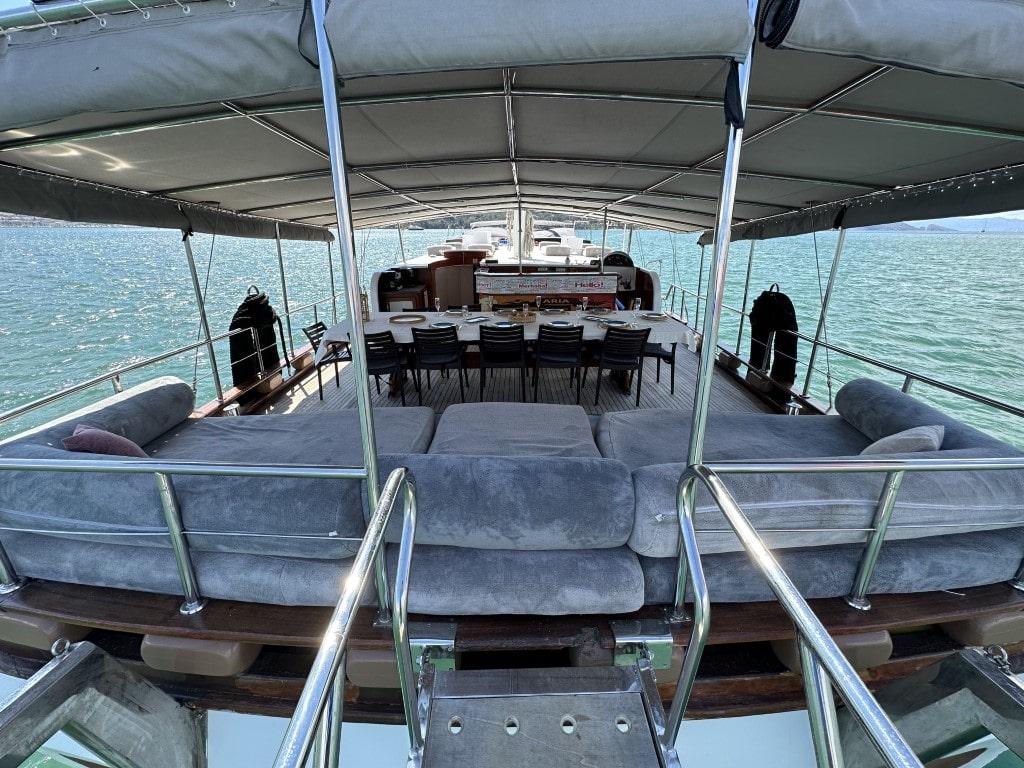 Upper deck lounge area with U-shaped seating, dining table and fabric canopy overhead