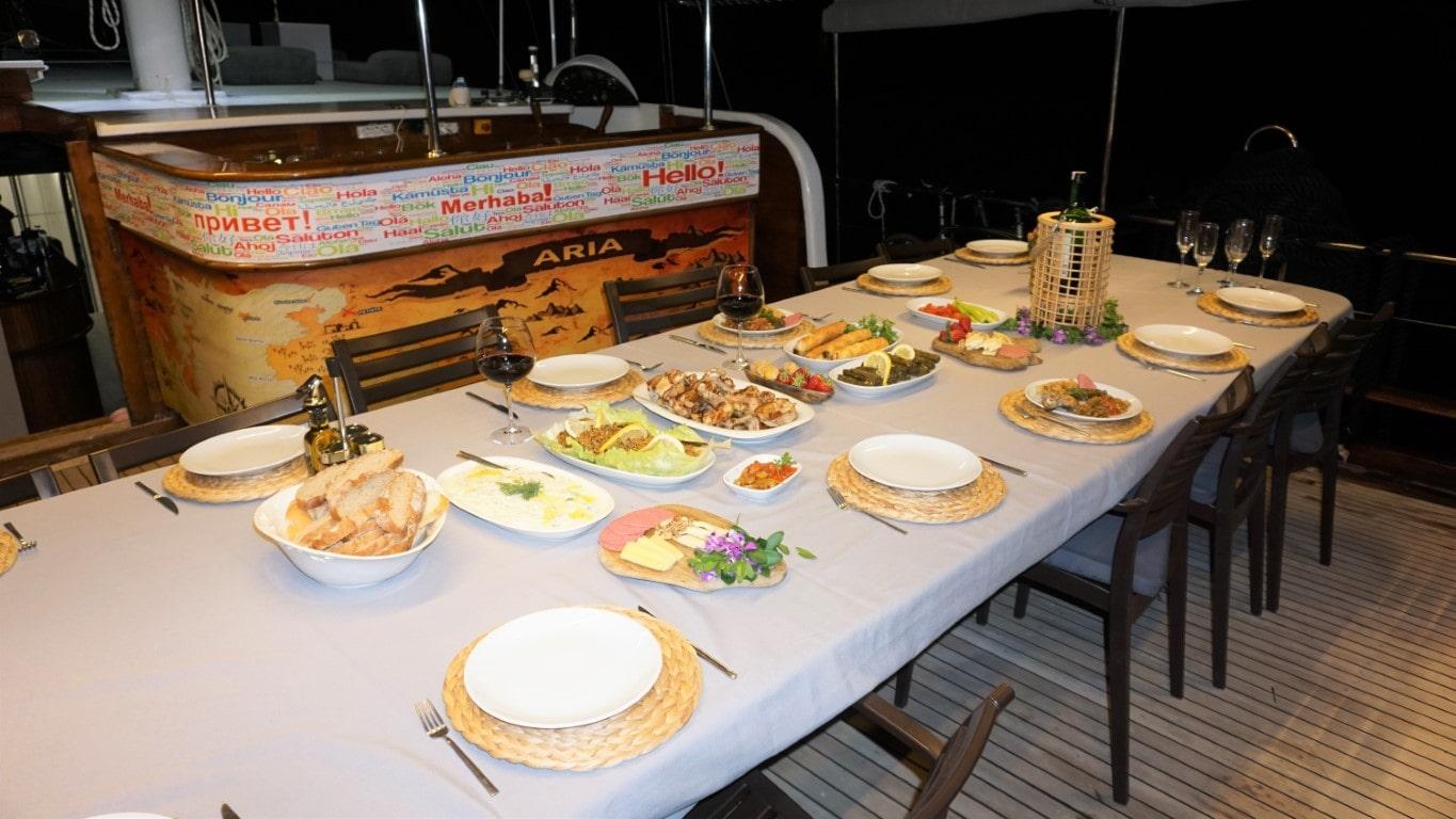 yacht aft deck dining table with elaborate meal spread including bread plates and wine glasses